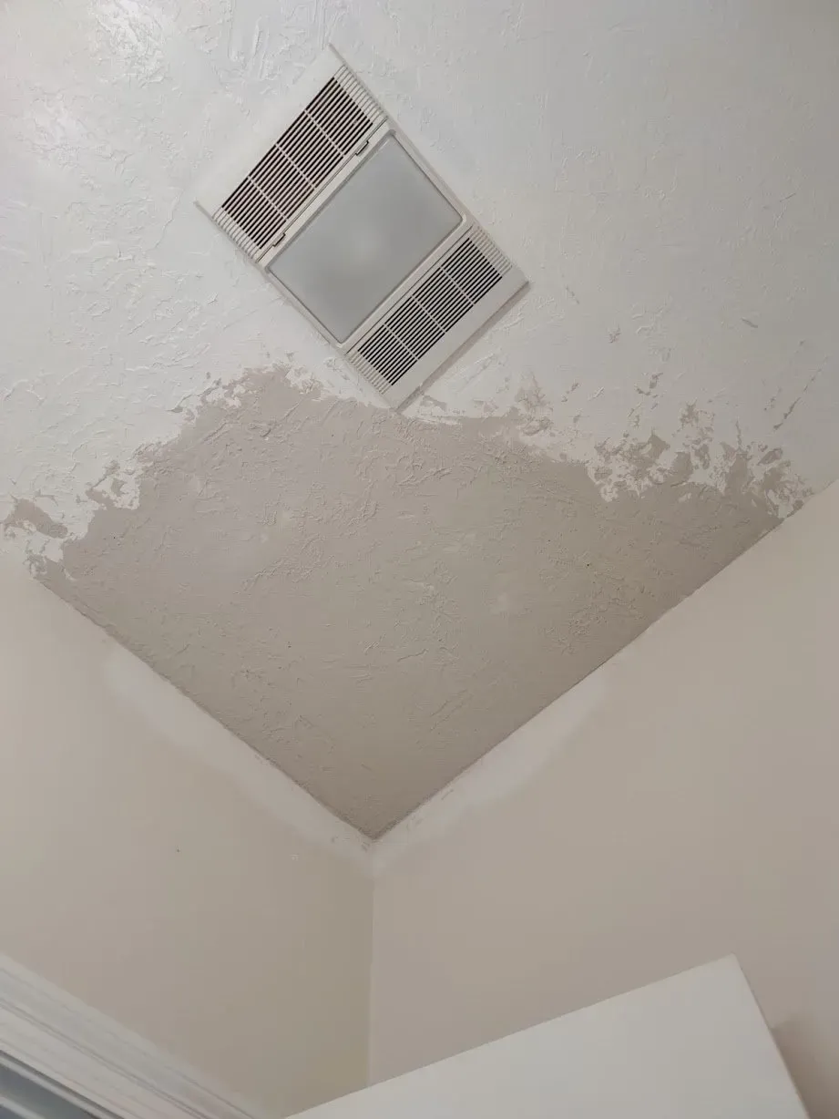 A bathroom with a ceiling fan and a drain on it.