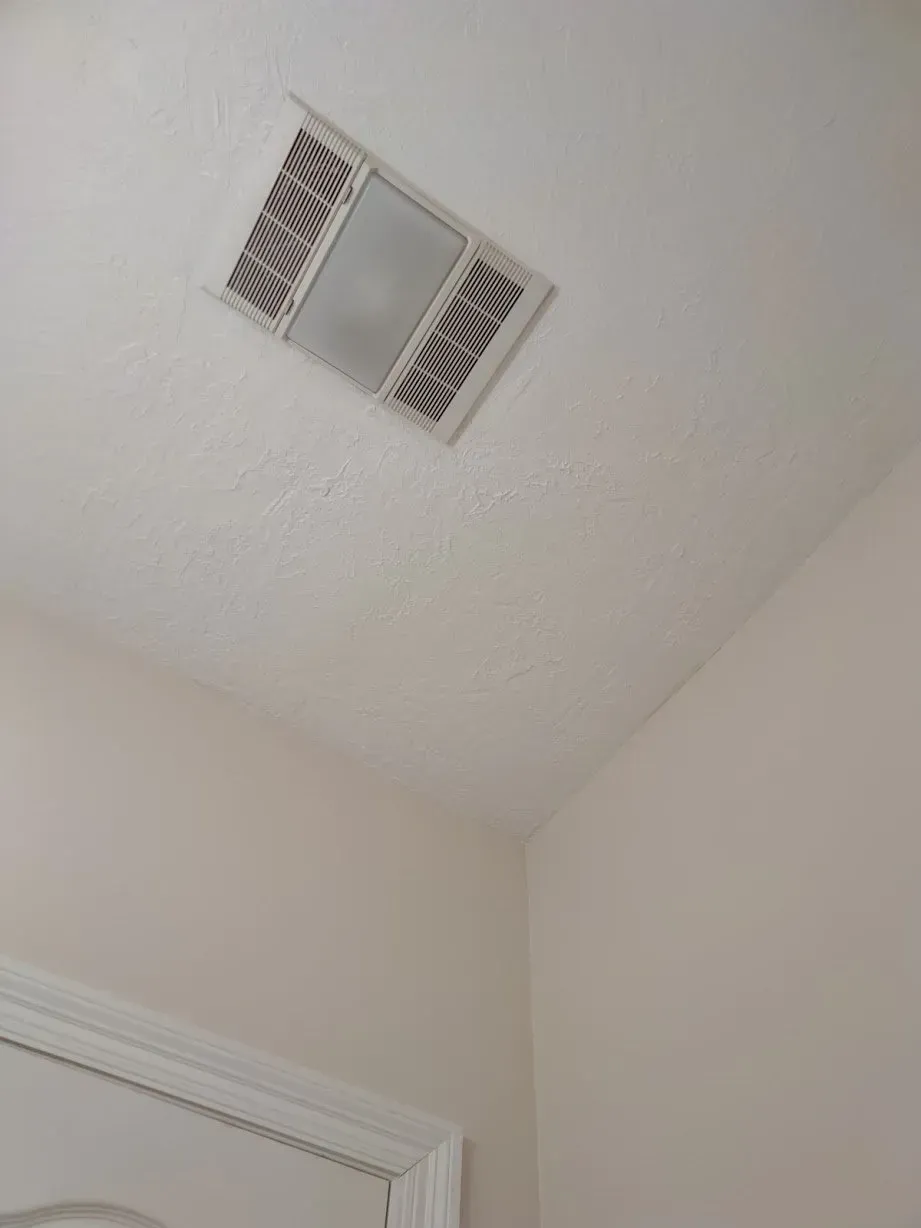 A bathroom with a ceiling fan and a light on it.
