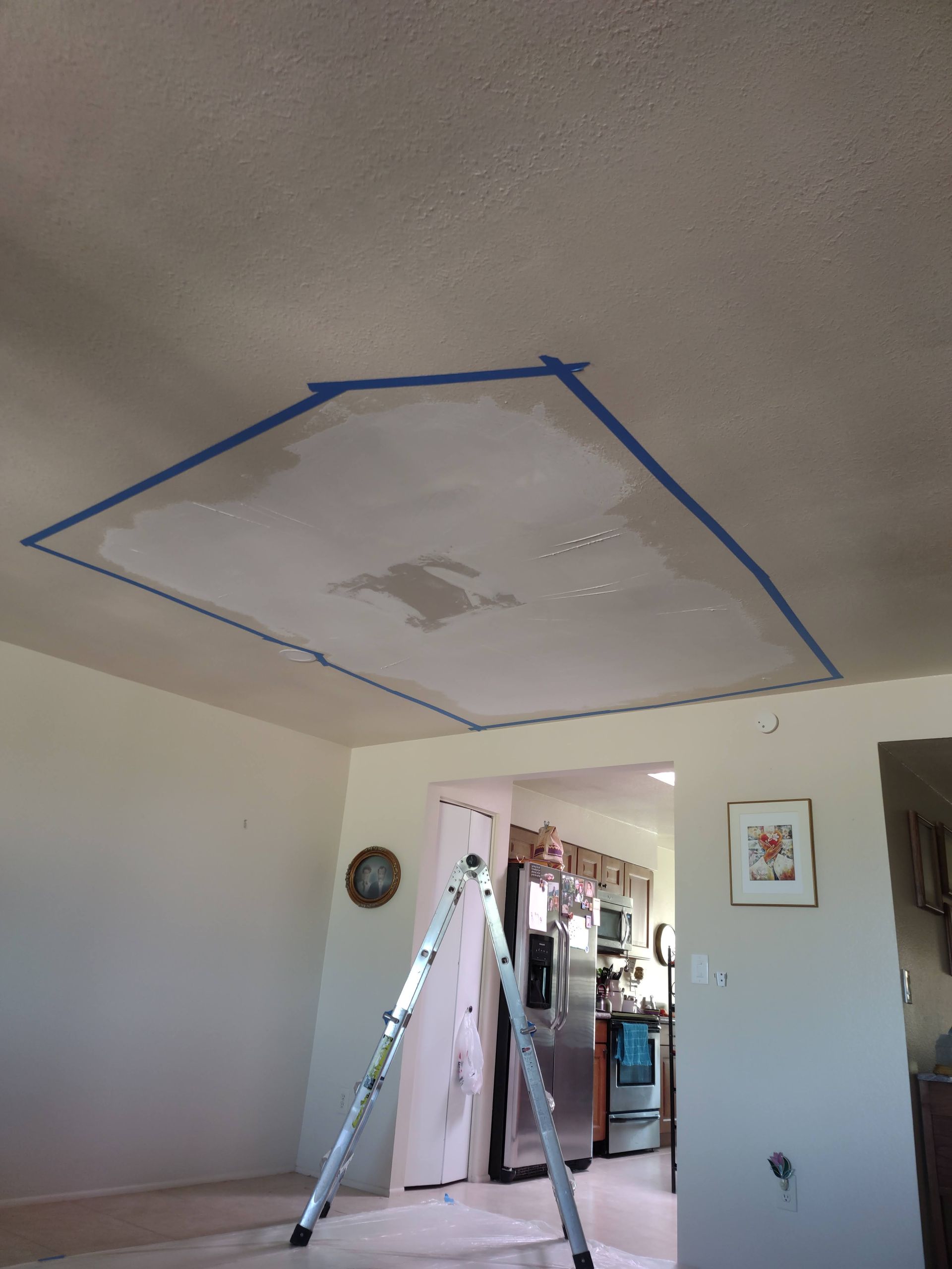 A room with a ladder and a blue tape on the ceiling