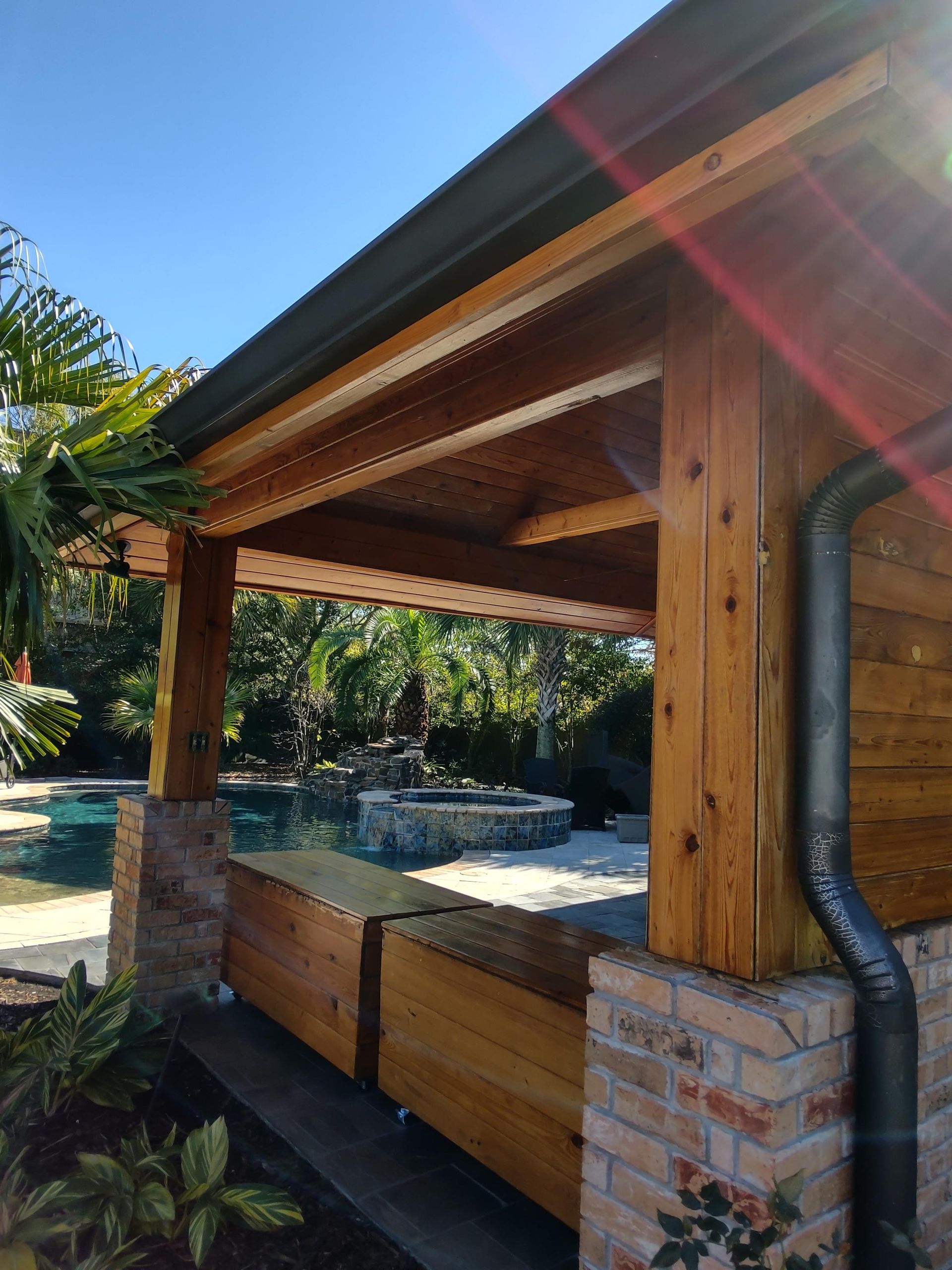 A wooden structure with a roof over a swimming pool.