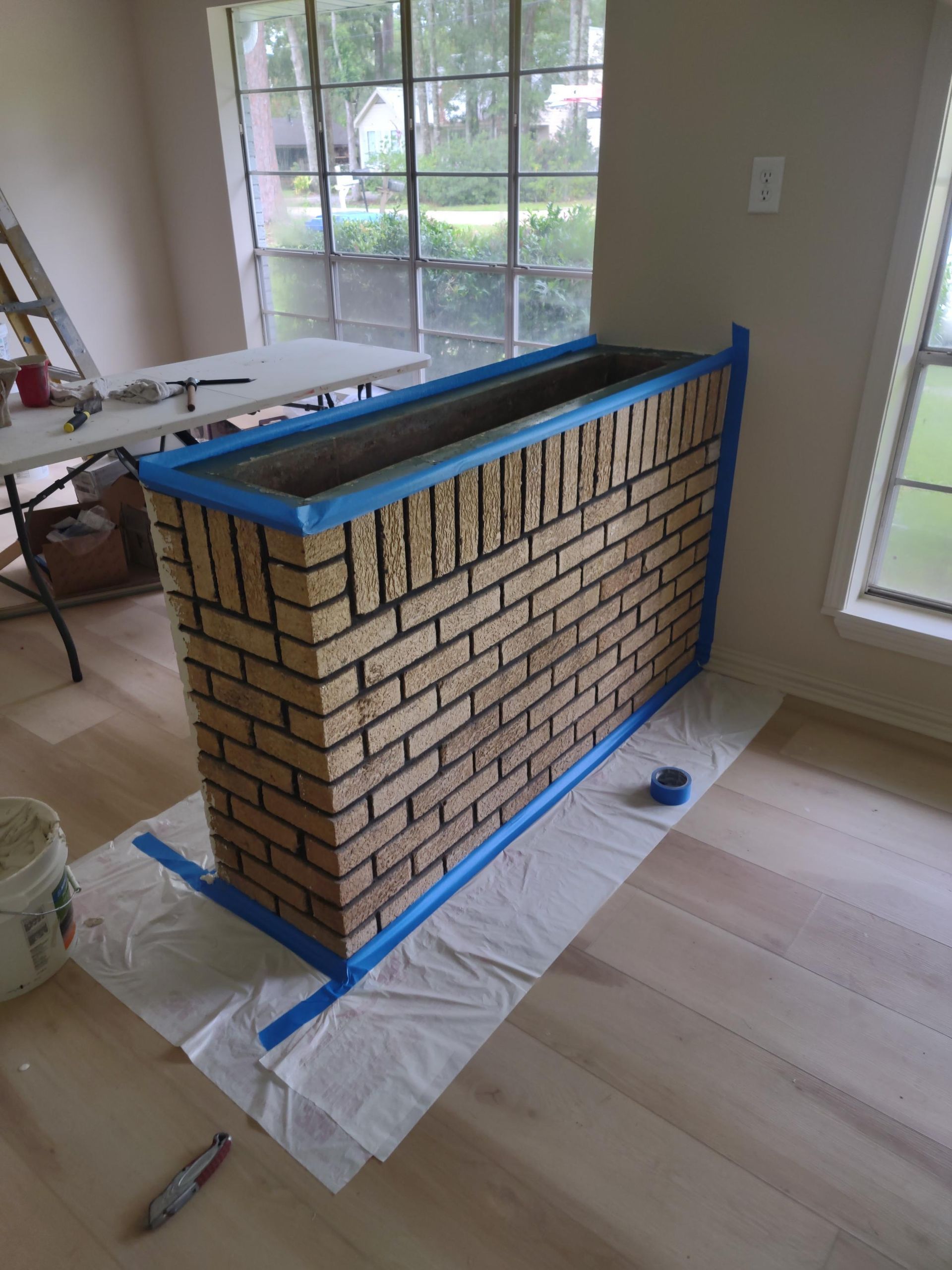 A brick fireplace is being painted in a living room.