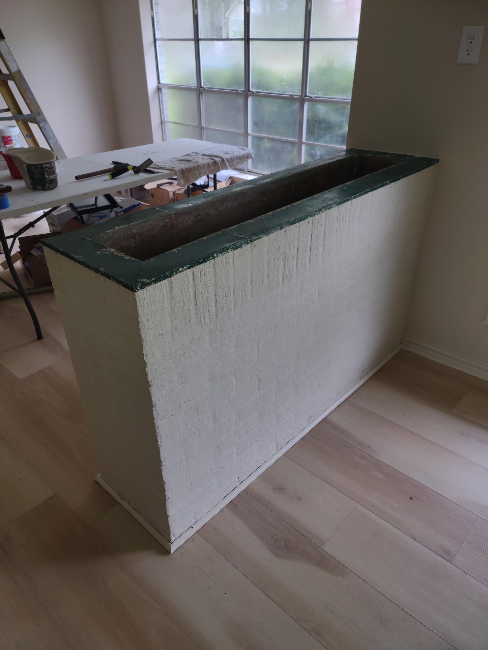 A white wall with a green trim is in a room next to a window.