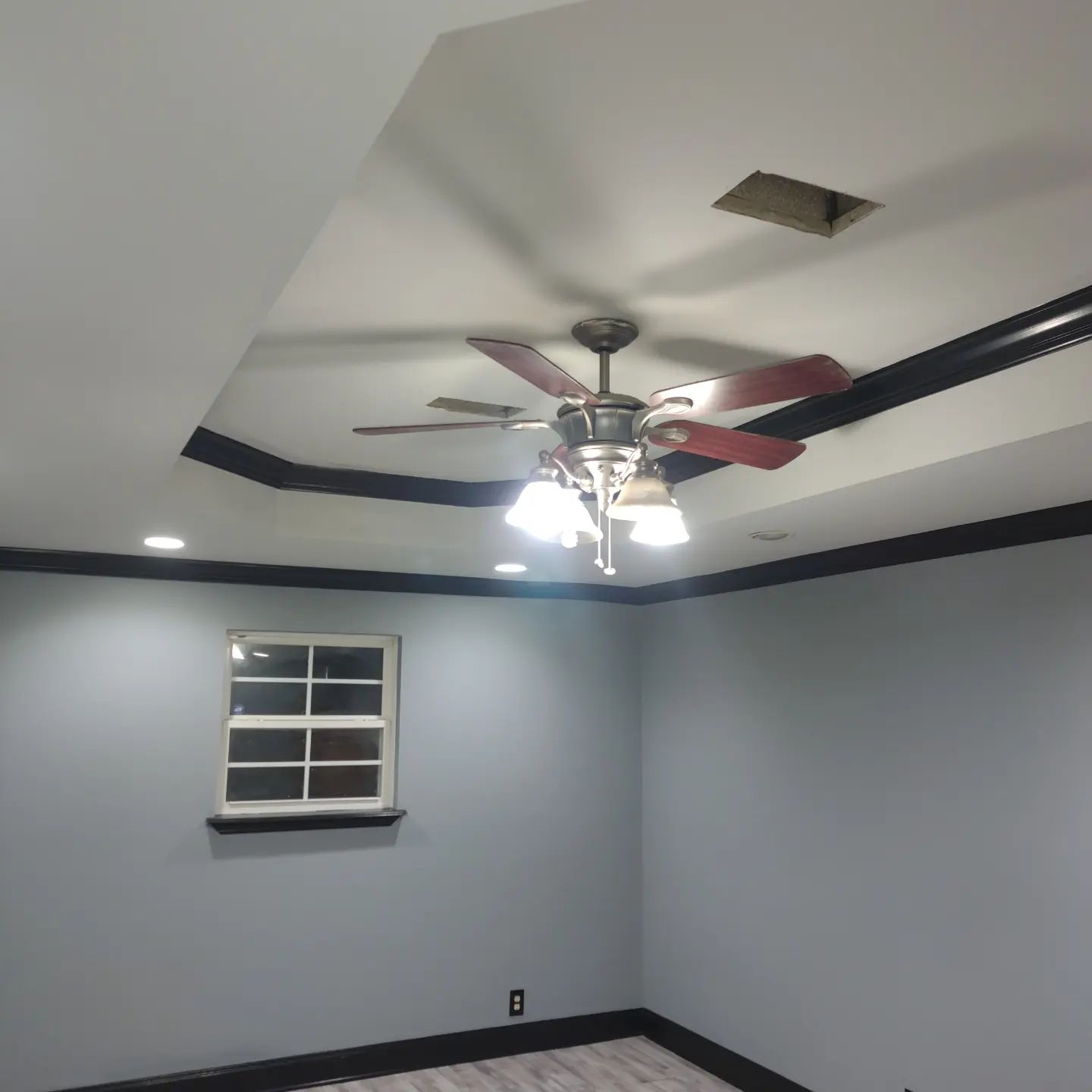 A room with a ceiling fan and a window