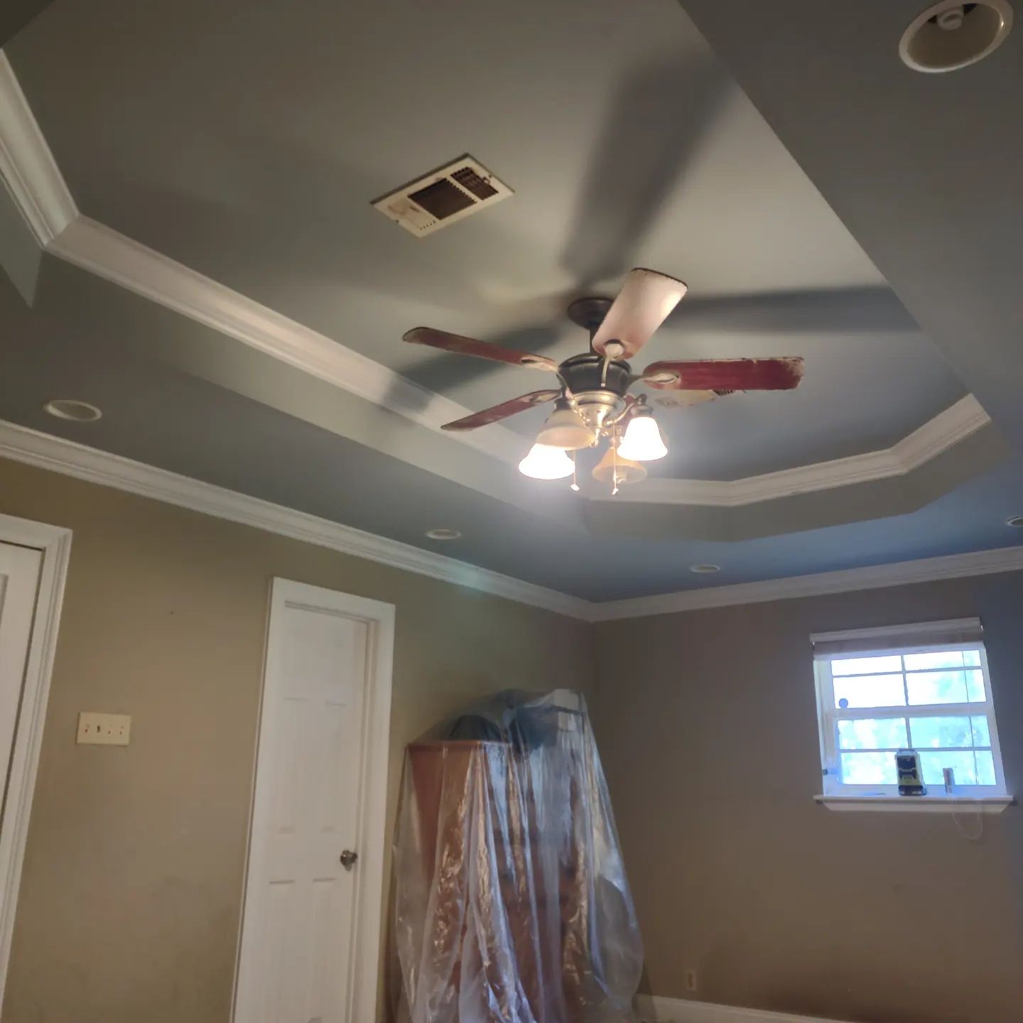 A bedroom with a ceiling fan and a window.