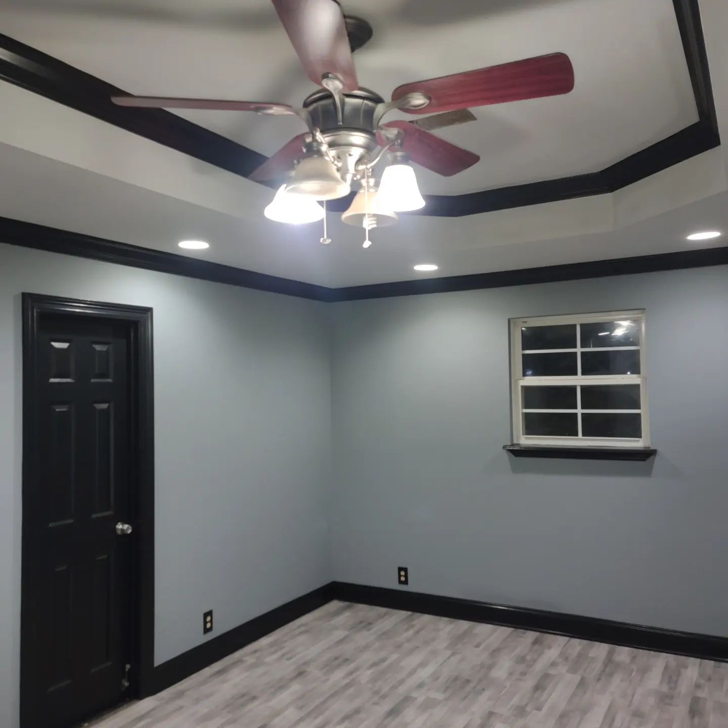 An empty room with a ceiling fan and a window