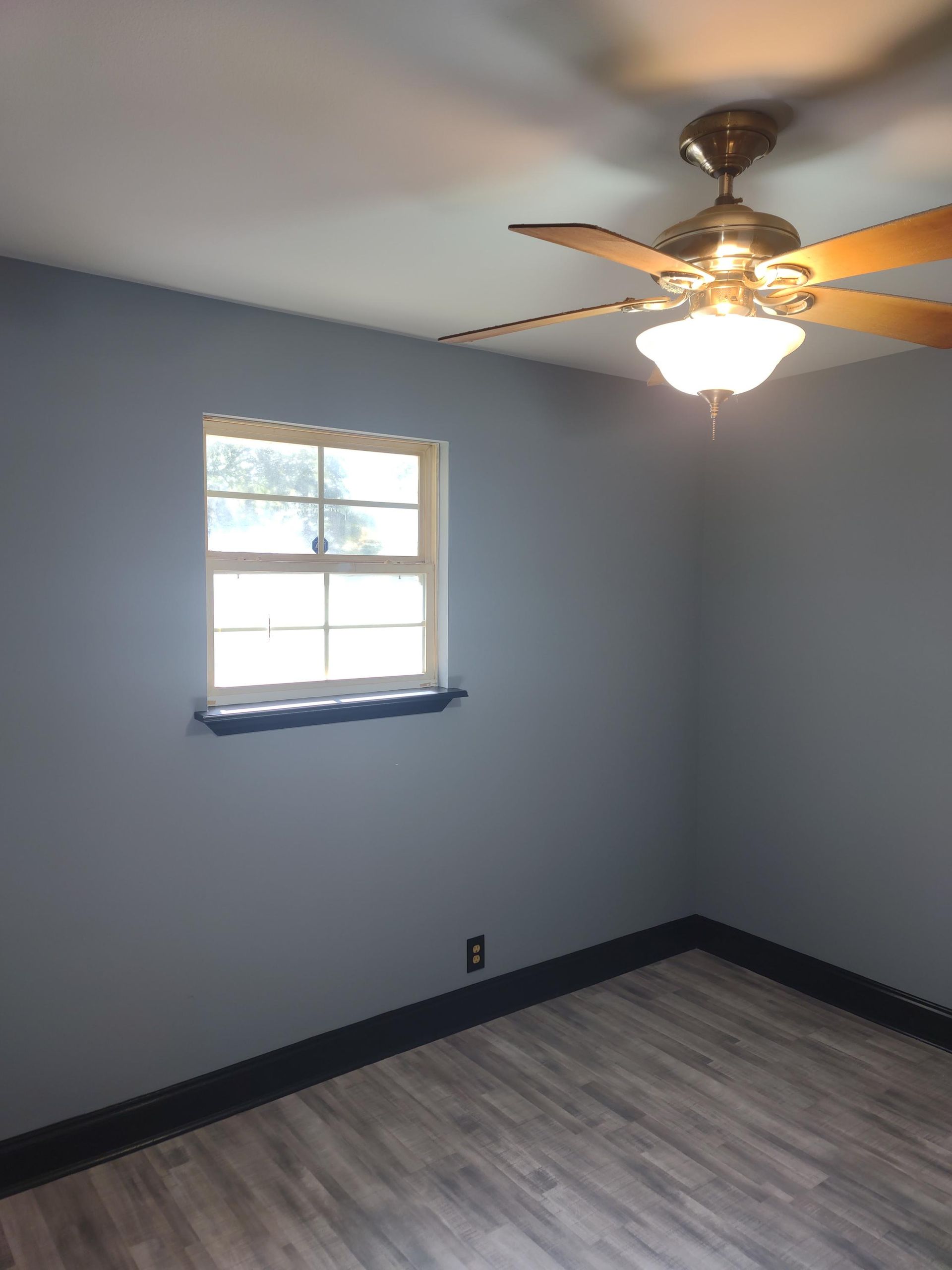 A bedroom with a ceiling fan and a window.
