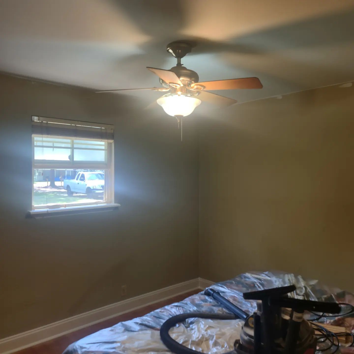 A bedroom with a ceiling fan and a window