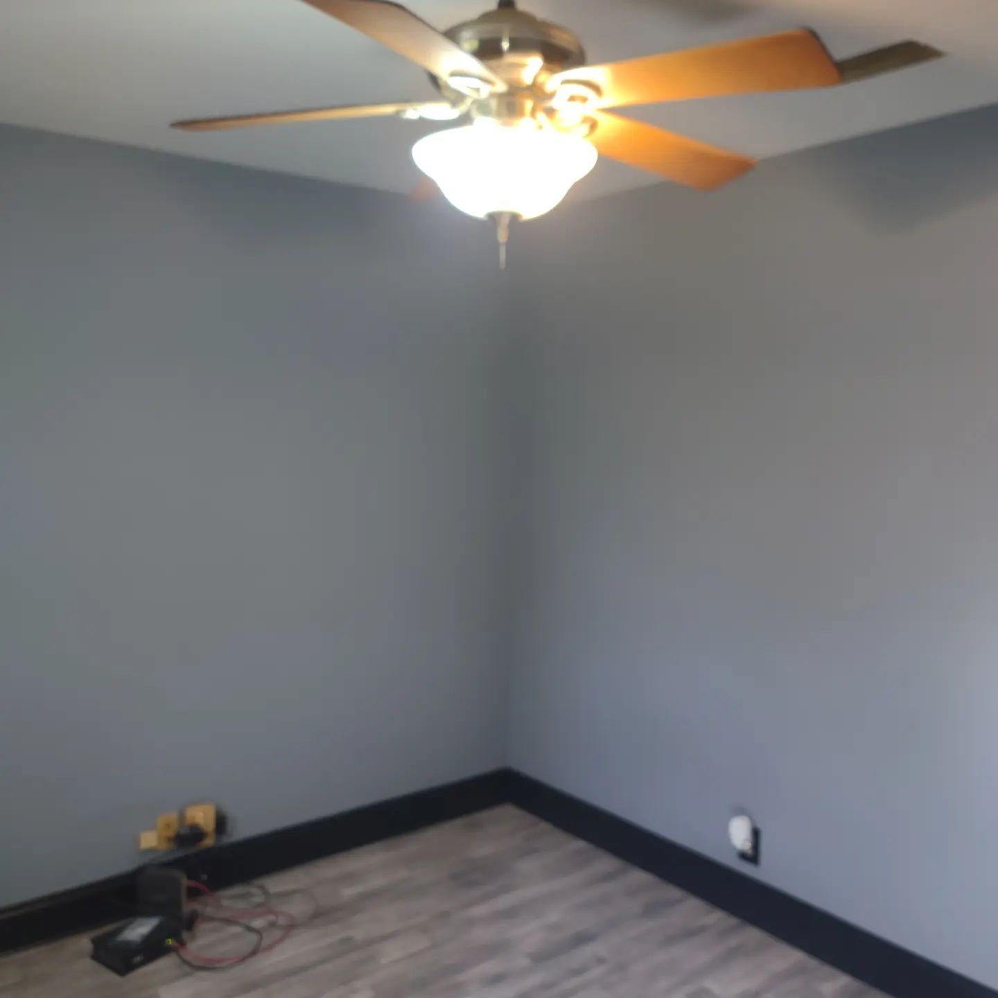 A room with a ceiling fan and a light on the ceiling.
