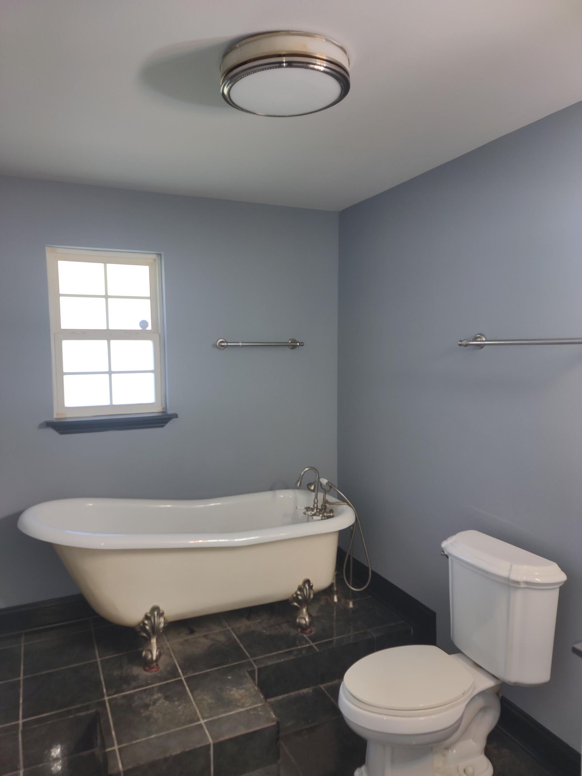 A bathroom with a tub and toilet and a window