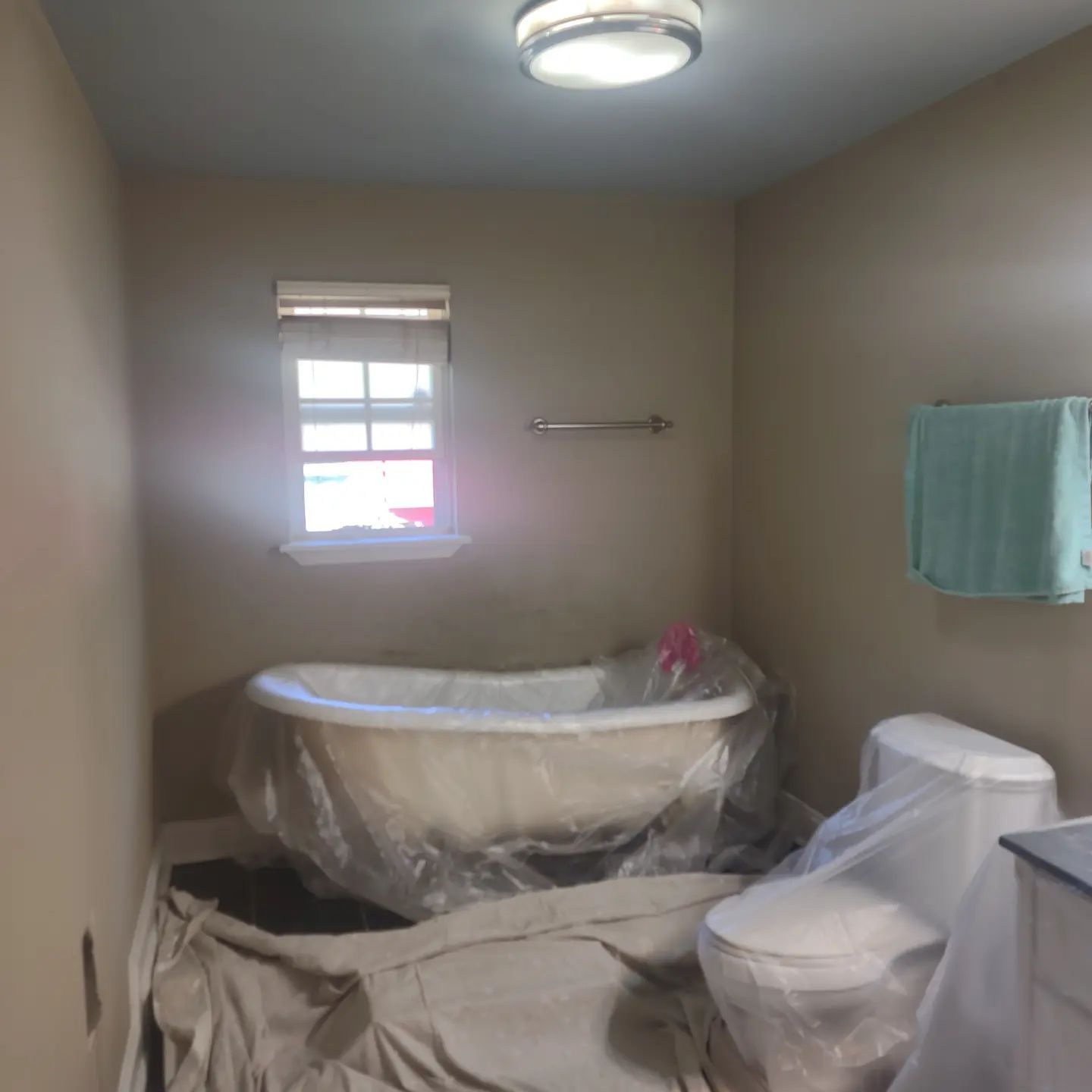 A bathroom with a tub , toilet , and window