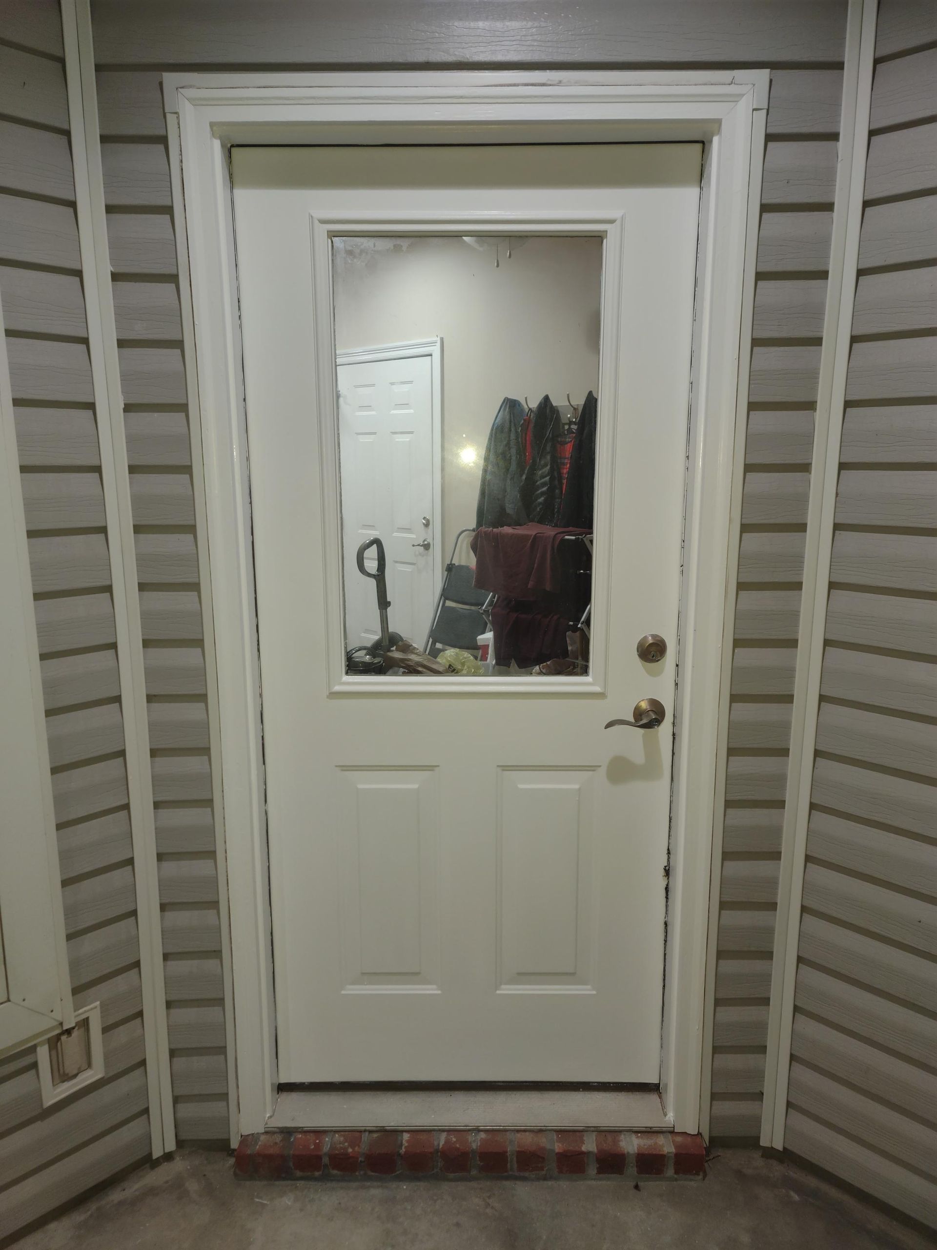 A white door with a window in the corner of a house