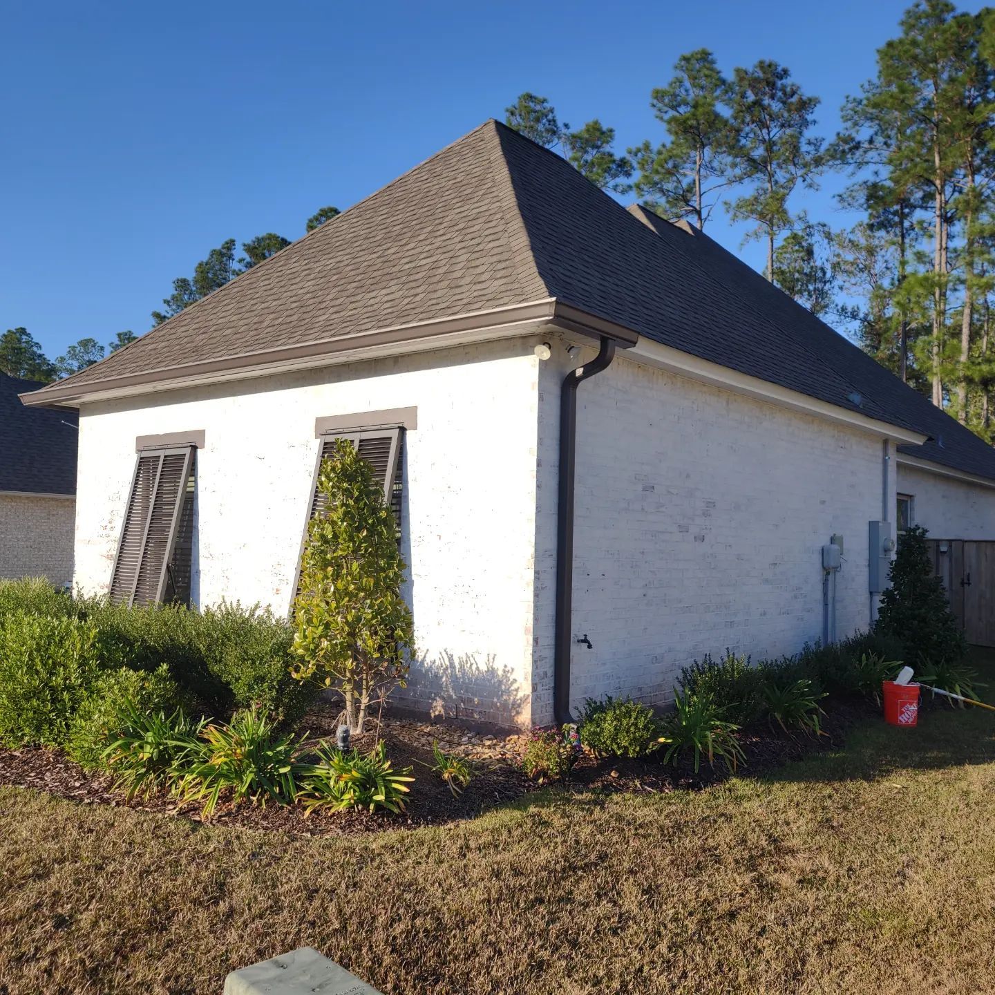 A white house with a gray roof and shutters