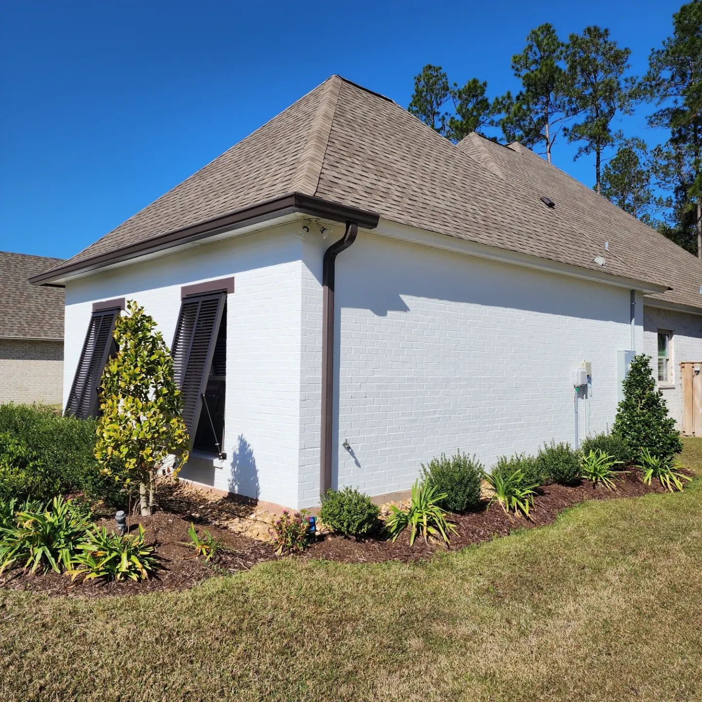 A white house with a brown roof and shutters on the windows
