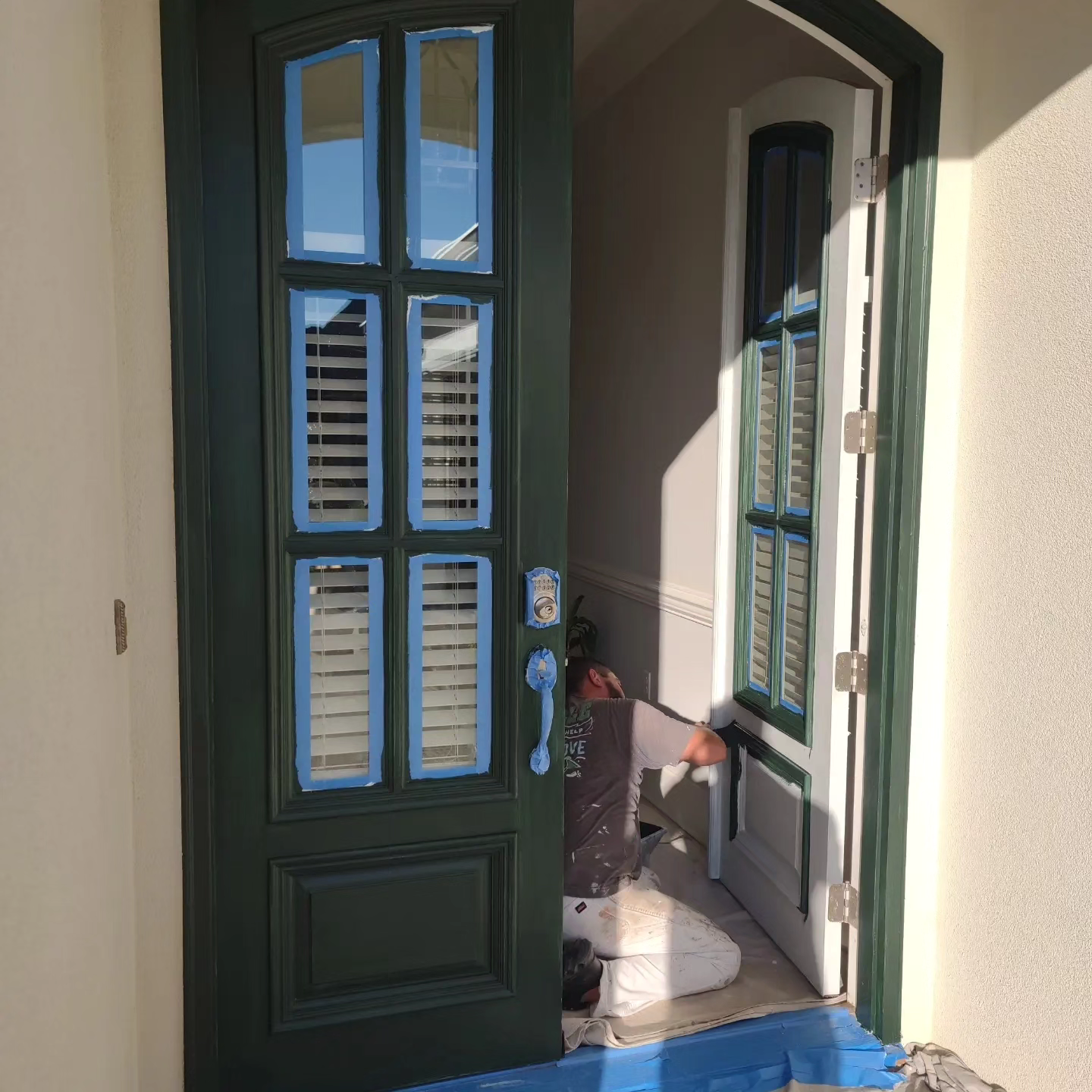 A green door with blue shutters is open to a room.