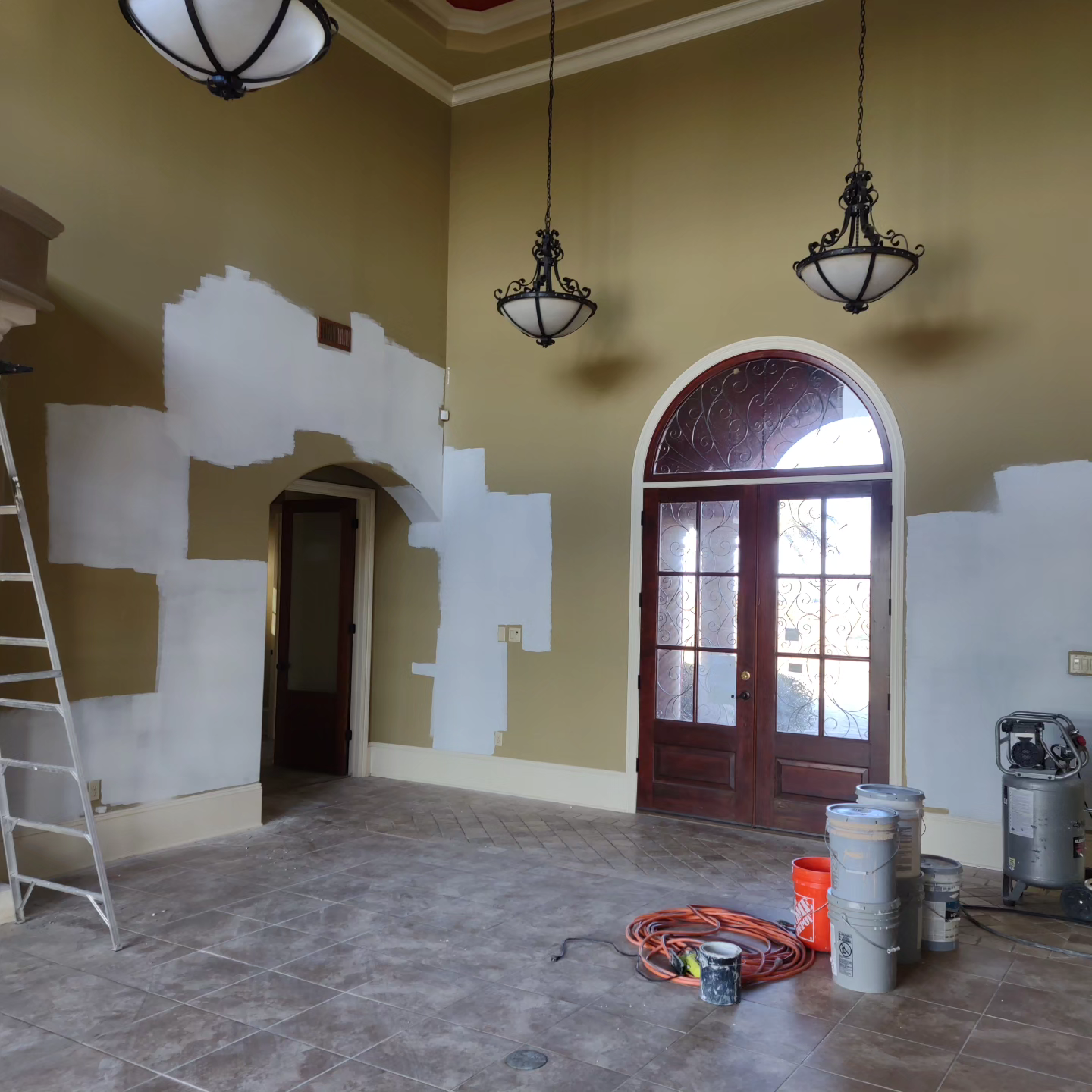 An empty room with a ladder and buckets of paint