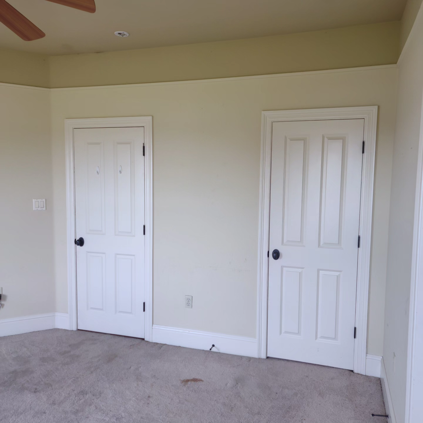 A bedroom with two white doors and a ceiling fan