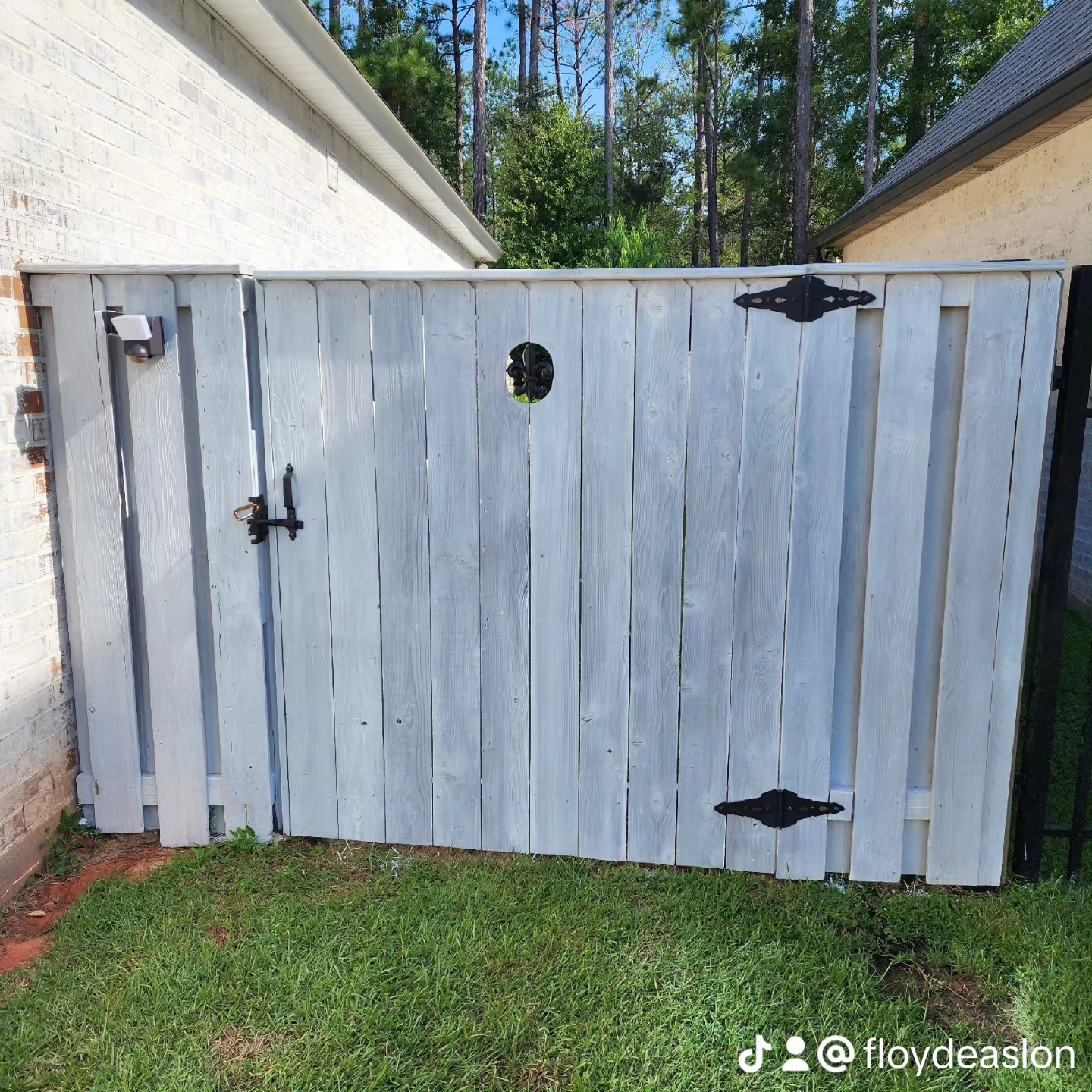 A white wooden fence is sitting in the grass next to a house.