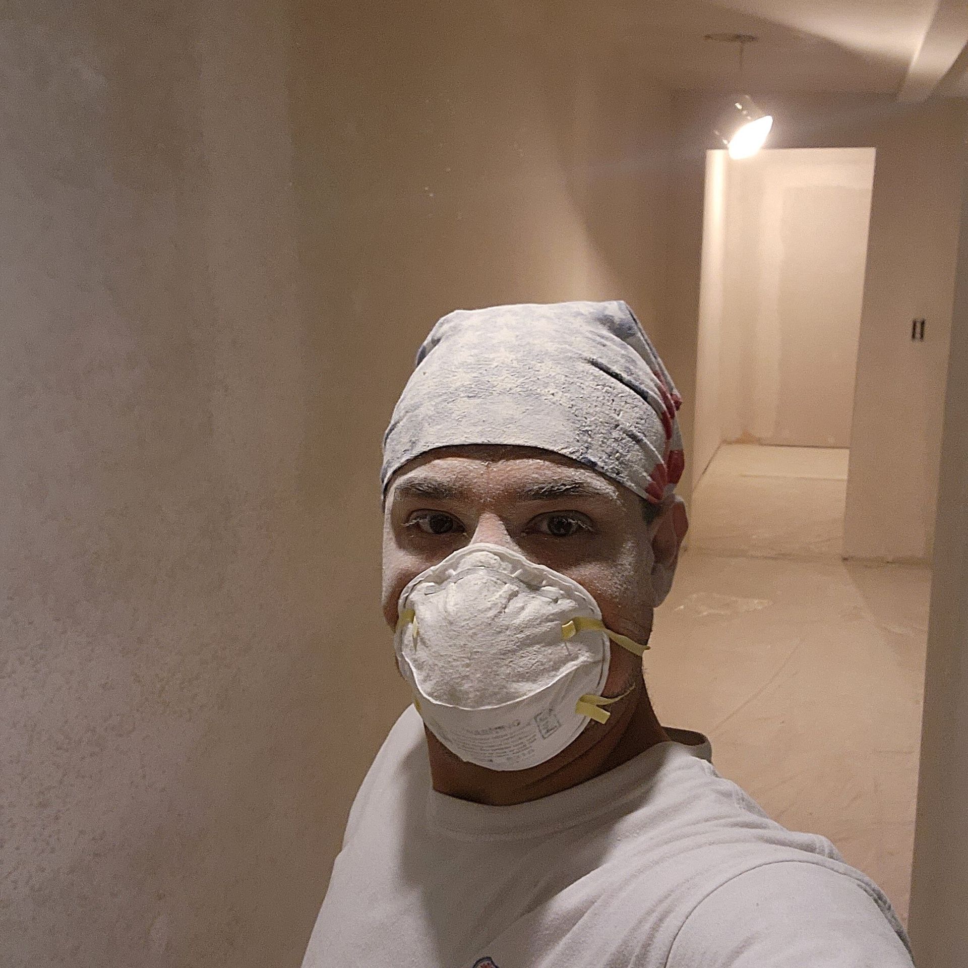 A man wearing a mask and a bandana is standing in a hallway