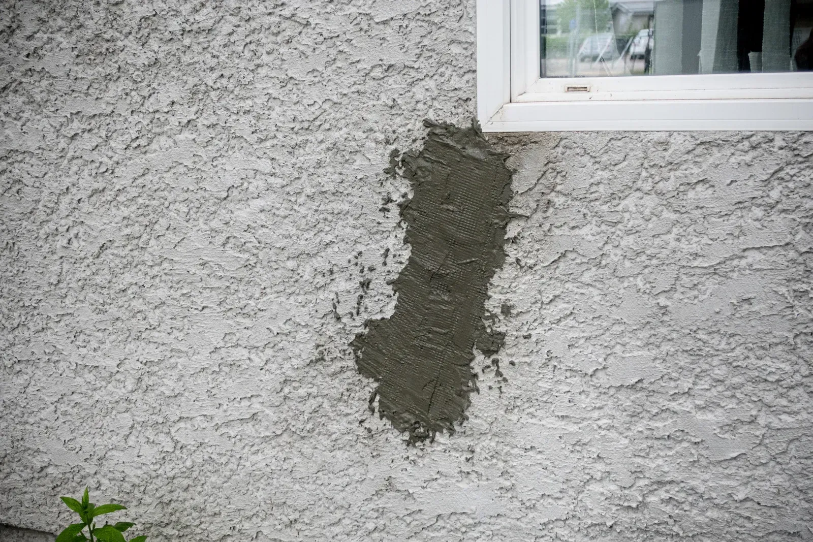 There is a hole in the wall next to a window.