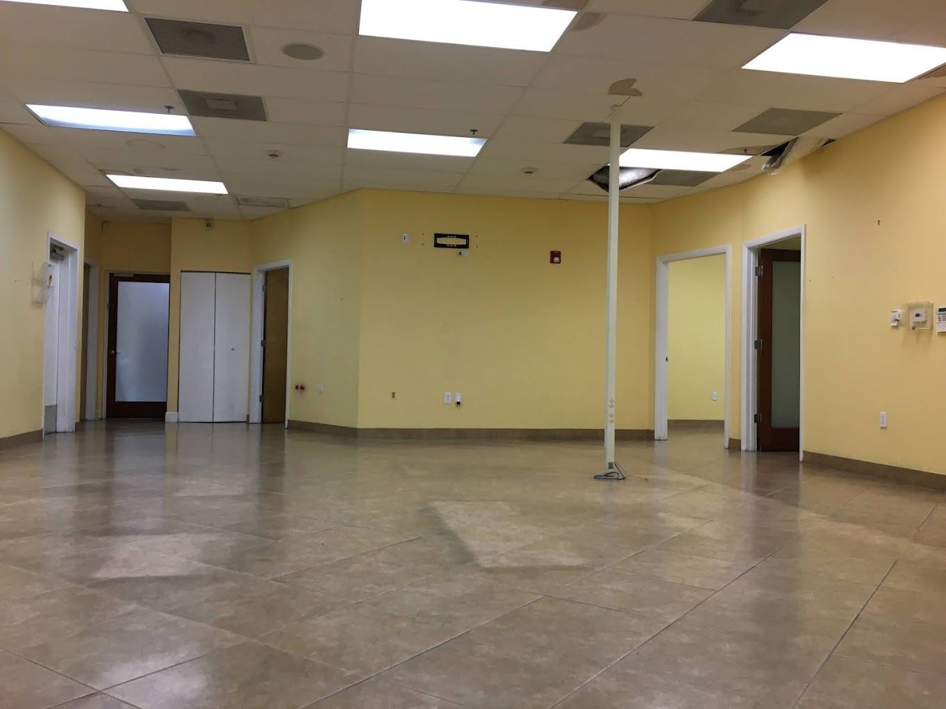 A large empty room with yellow walls and tile floors