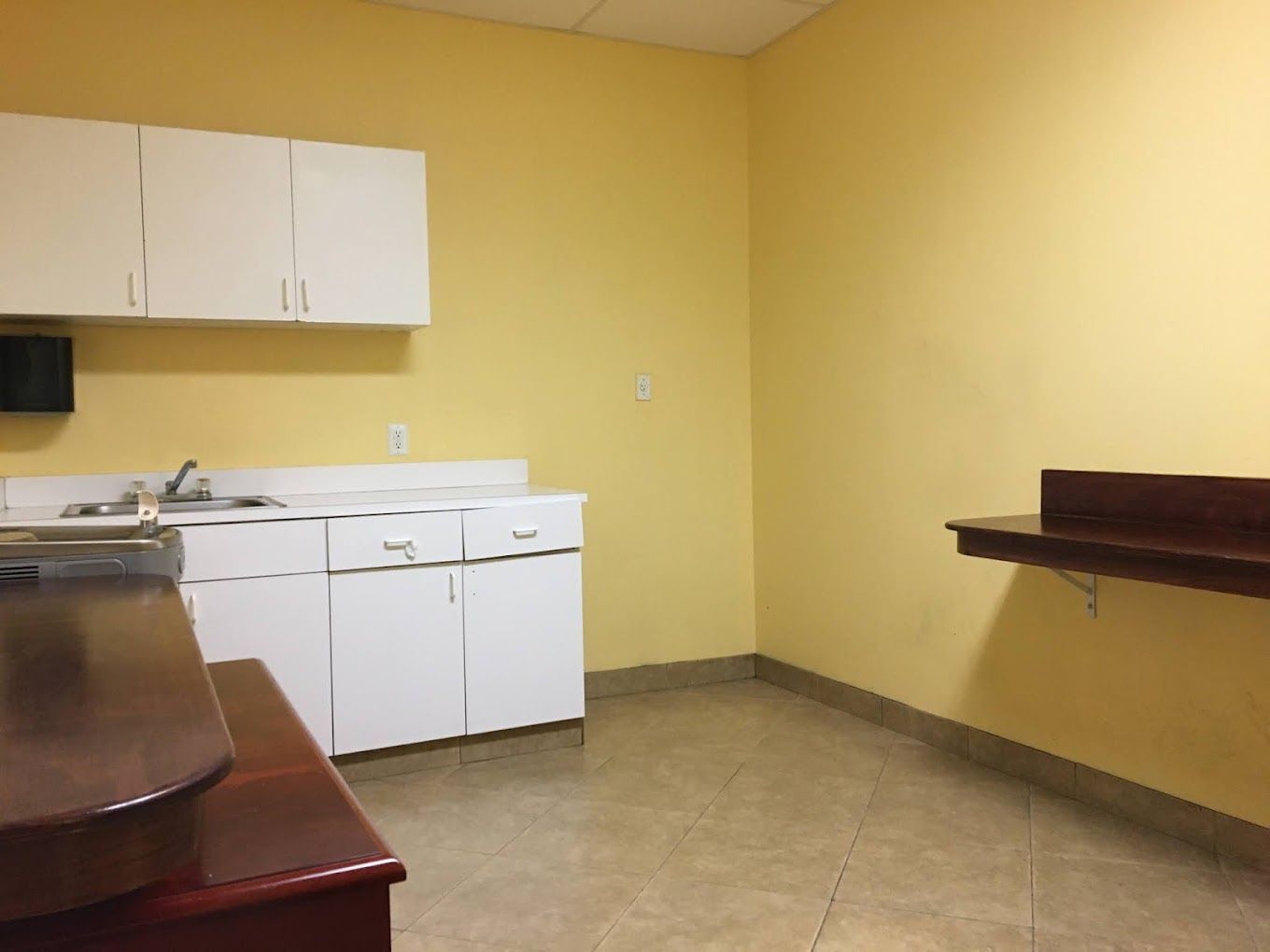 An empty kitchen with yellow walls and white cabinets