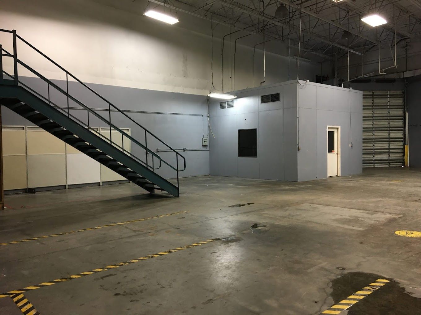 An empty warehouse with stairs and a door