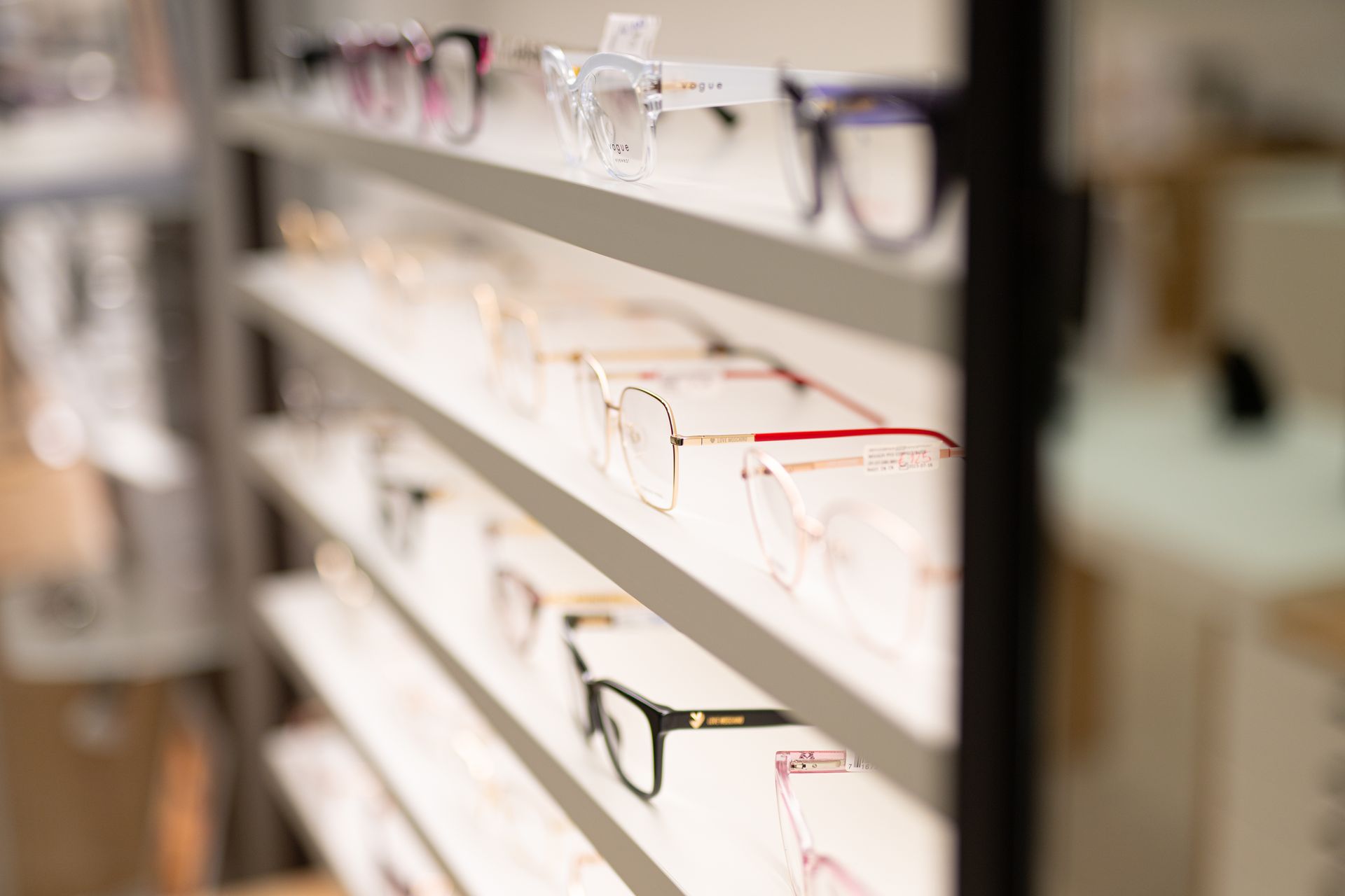 Occhiali esposti sugli scaffali di un negozio di ottica, con montature di vari stili e colori.
