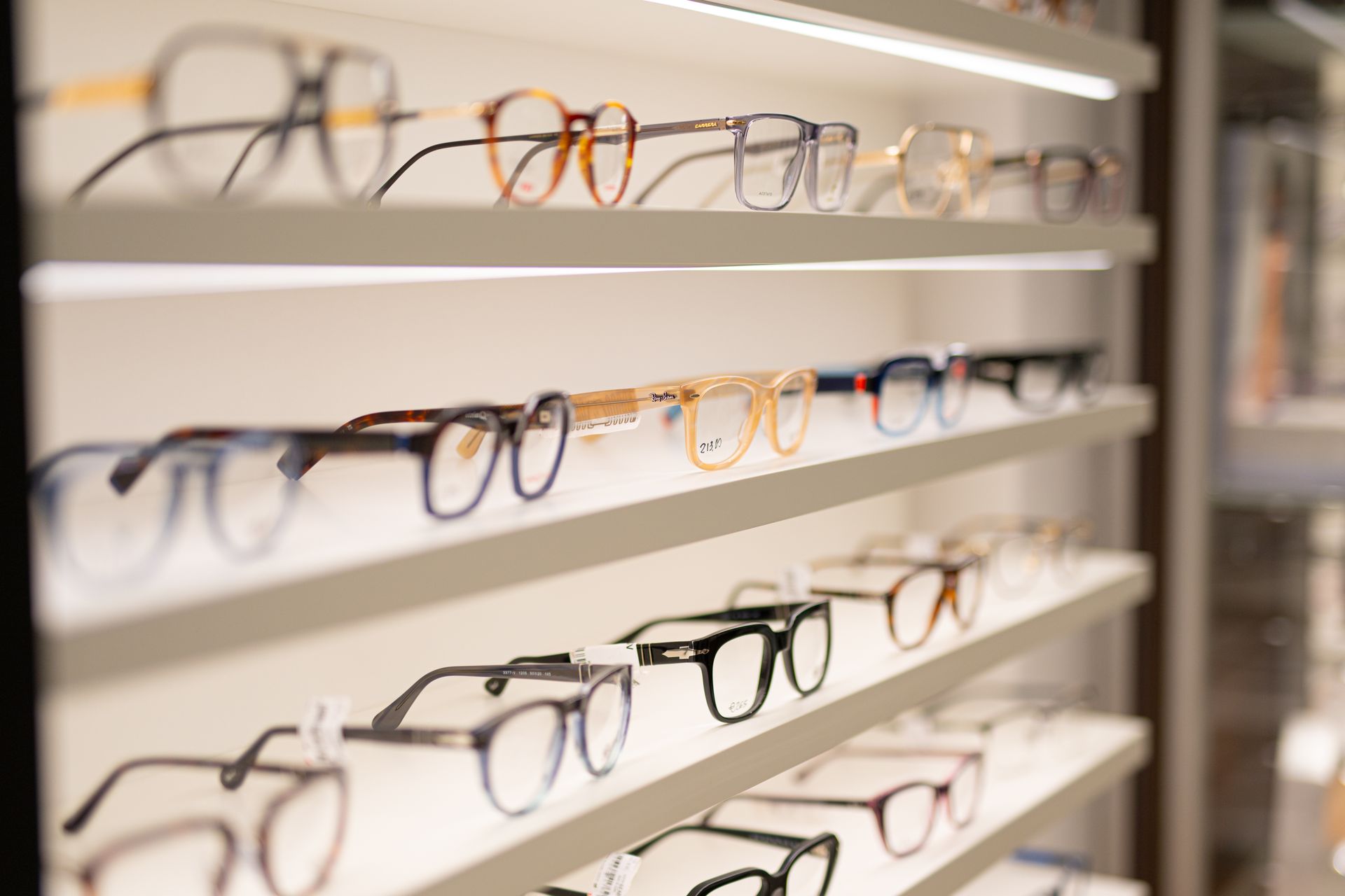 Occhiali esposti su scaffali illuminati in un negozio di ottica.