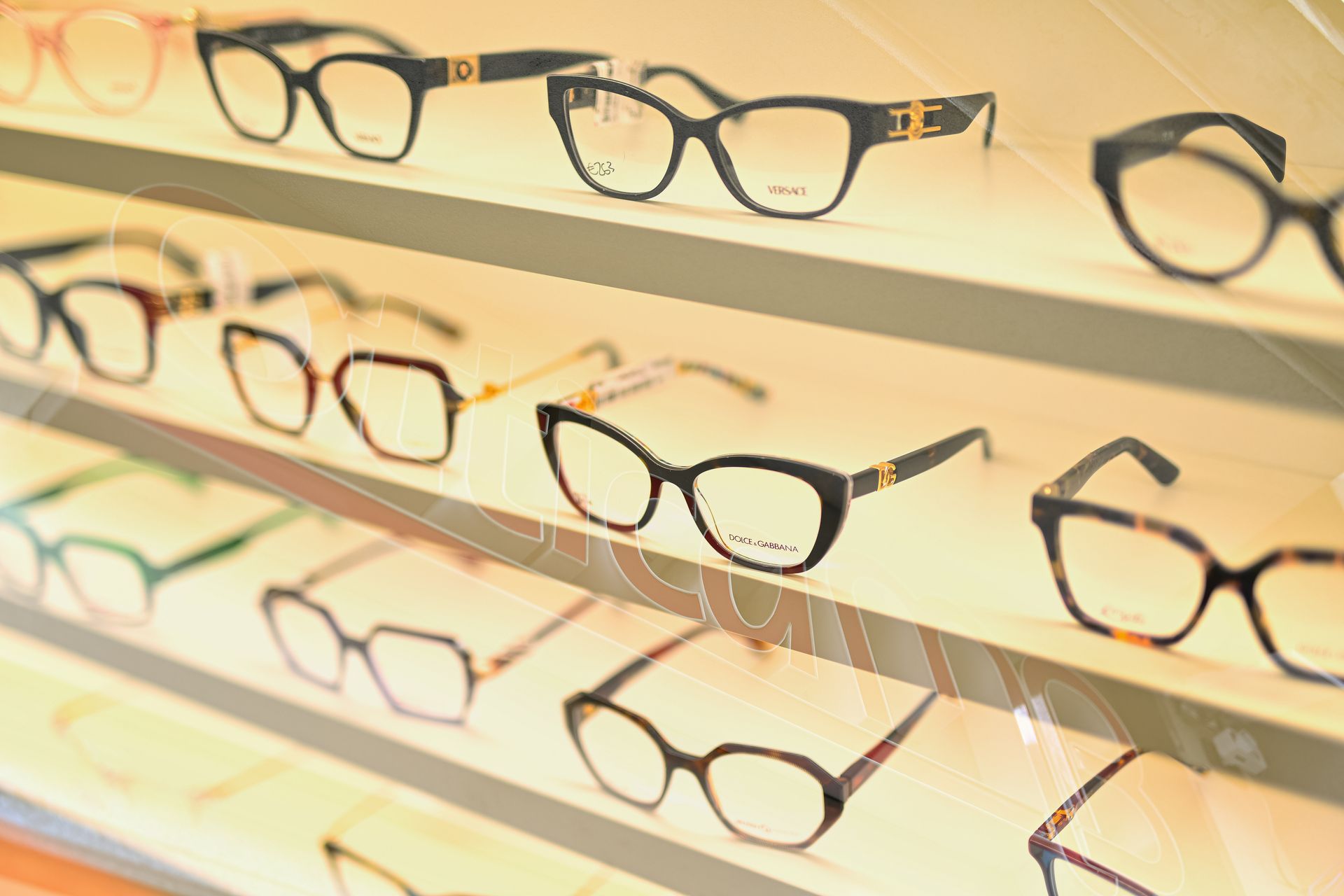 Occhiali esposti su scaffali illuminati all'interno di un negozio, con vari stili e colori visibili.