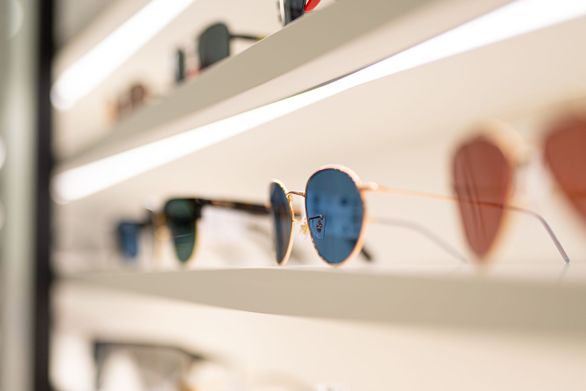 Occhiali da sole esposti su uno scaffale ben illuminato di un negozio.