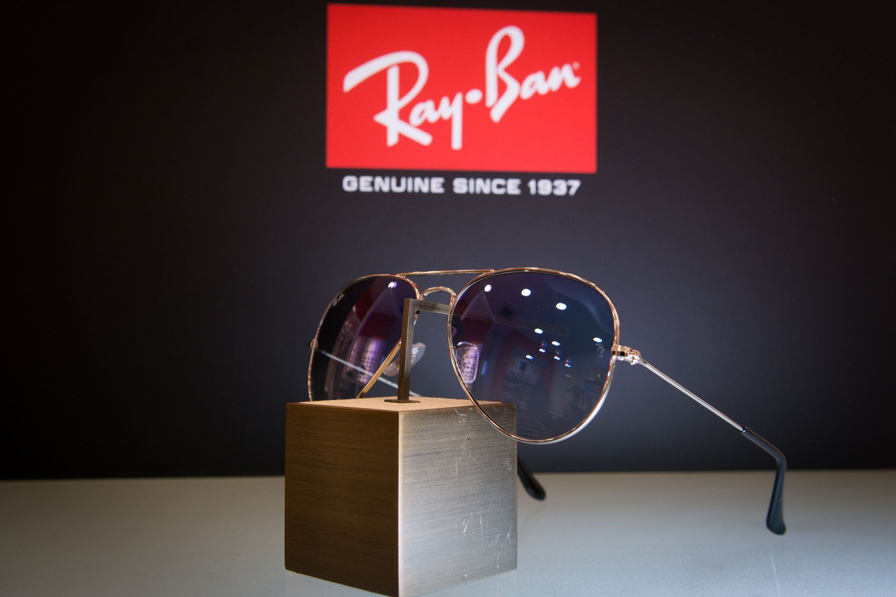 Occhiali da sole Ray-Ban Aviator su un supporto davanti al logo Ray-Ban.