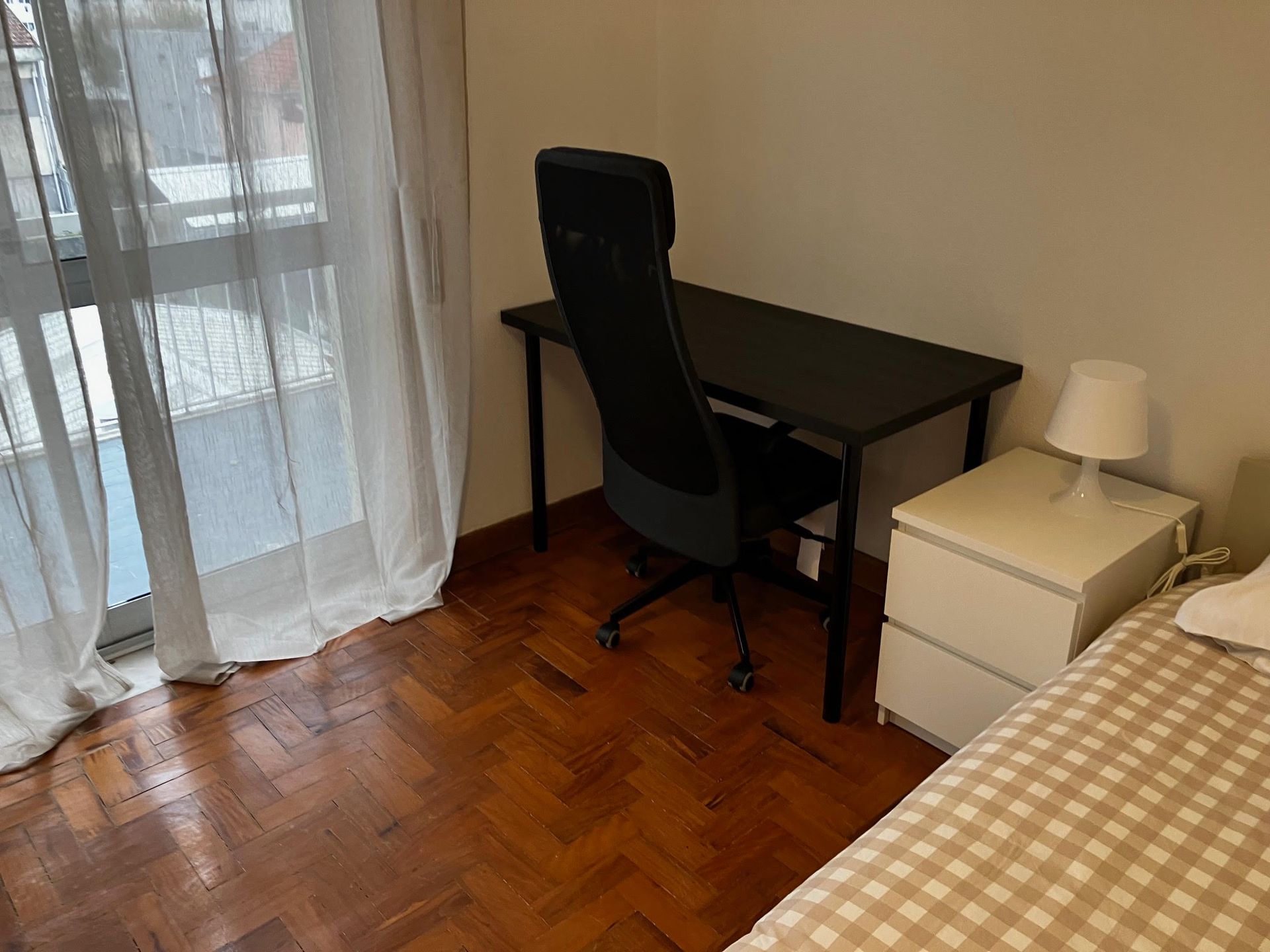 A bedroom with a desk chair and a nightstand