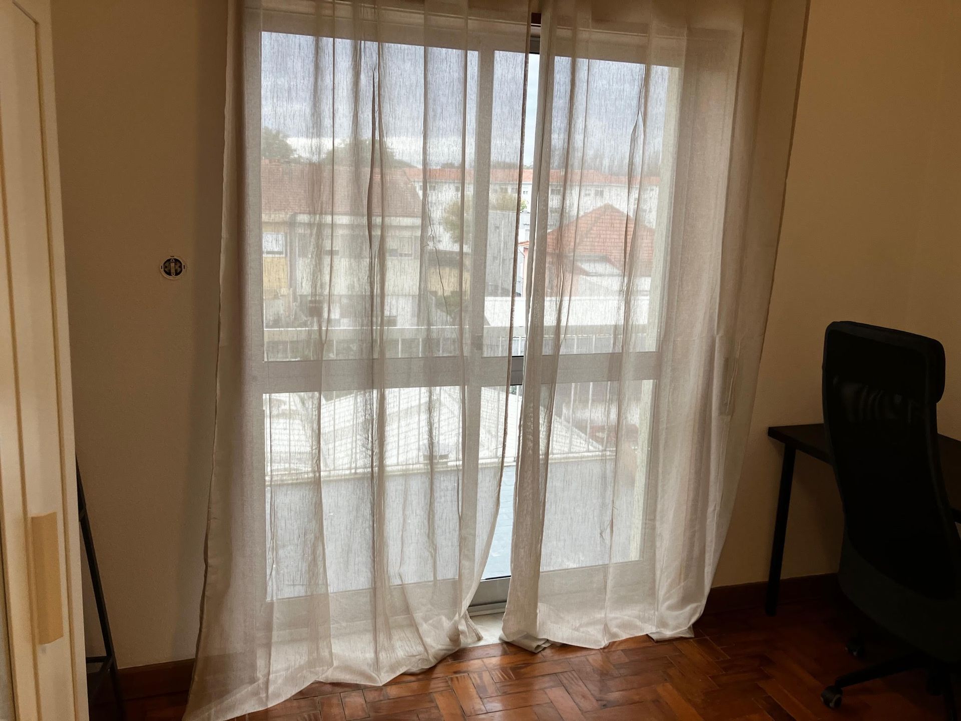 A room with a sliding glass door and white curtains