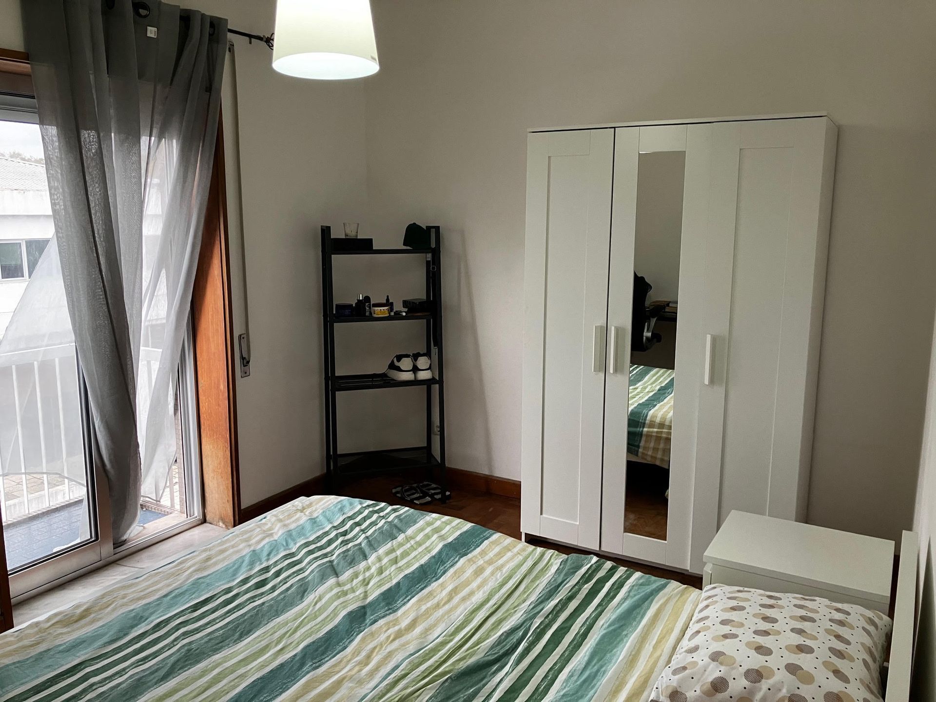 A bedroom with a striped bed and a white wardrobe
