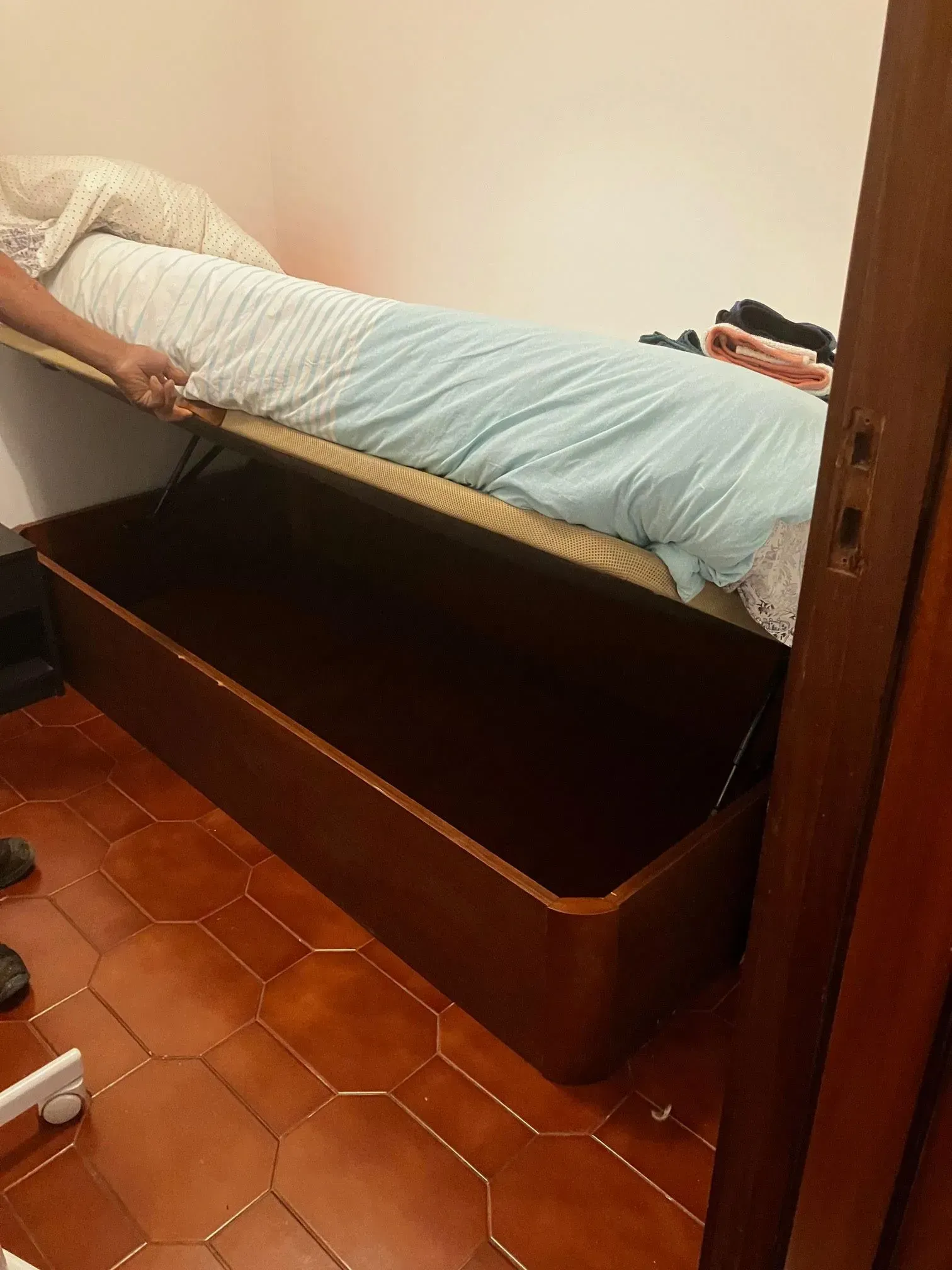 A person is laying on a bed with the lid open