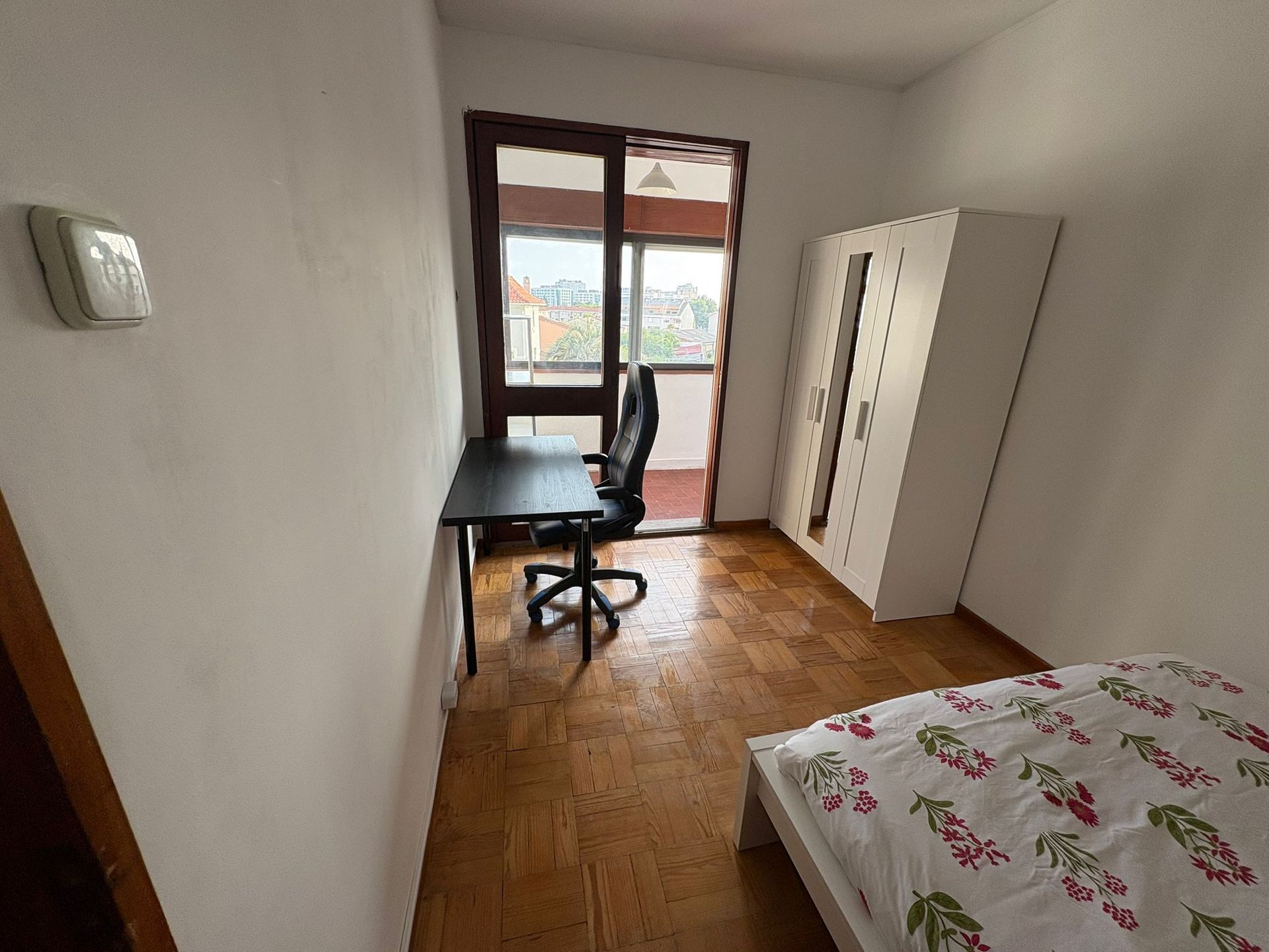A bedroom with a striped bed and a white wardrobe