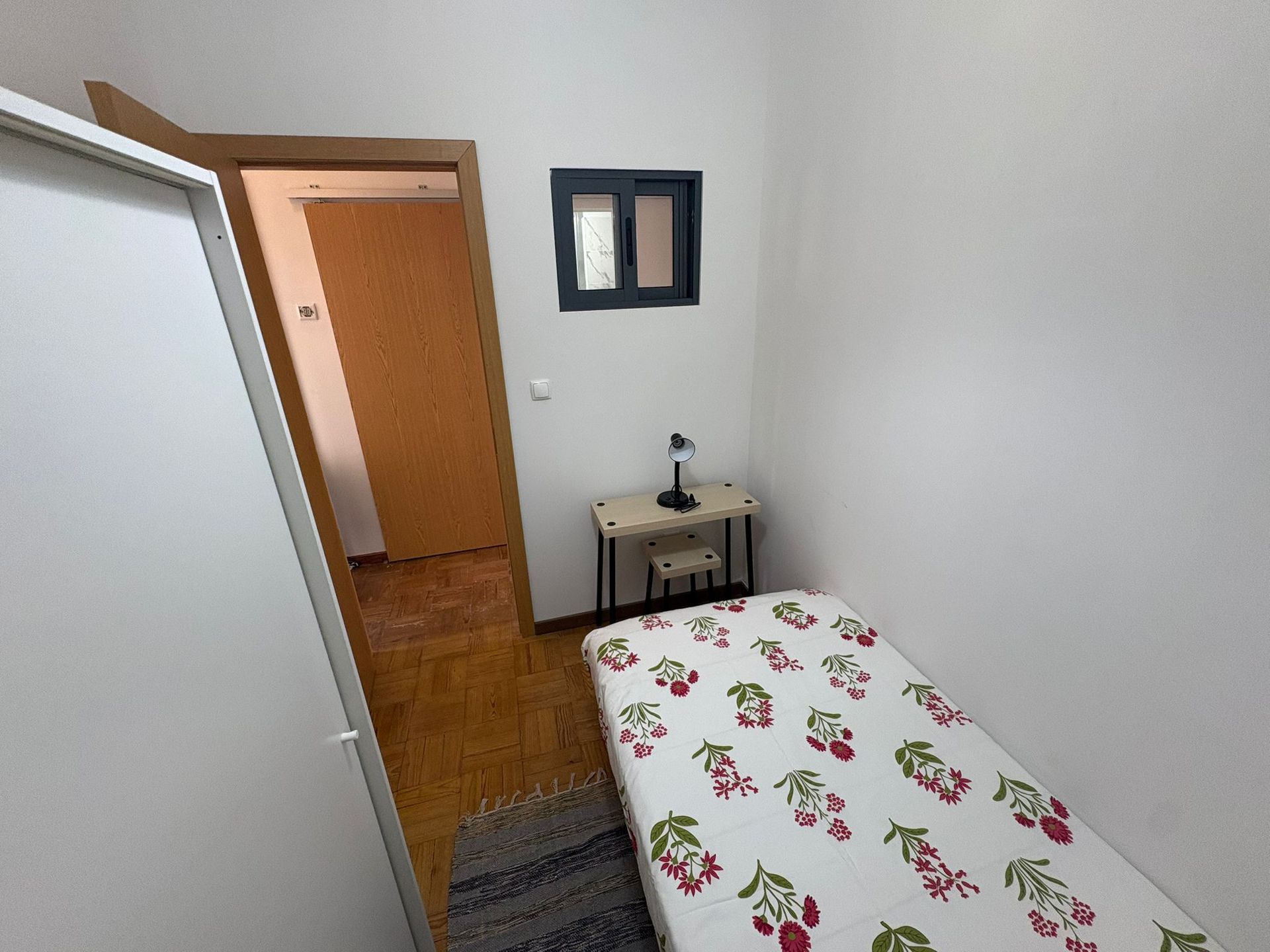 A bedroom with a white wardrobe and a black shelf