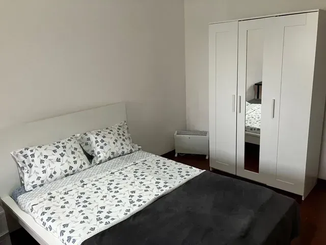 A bedroom with a bed , wardrobe and mirror.