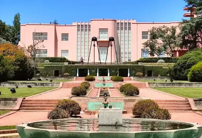 A large pink building with a fountain in front of it