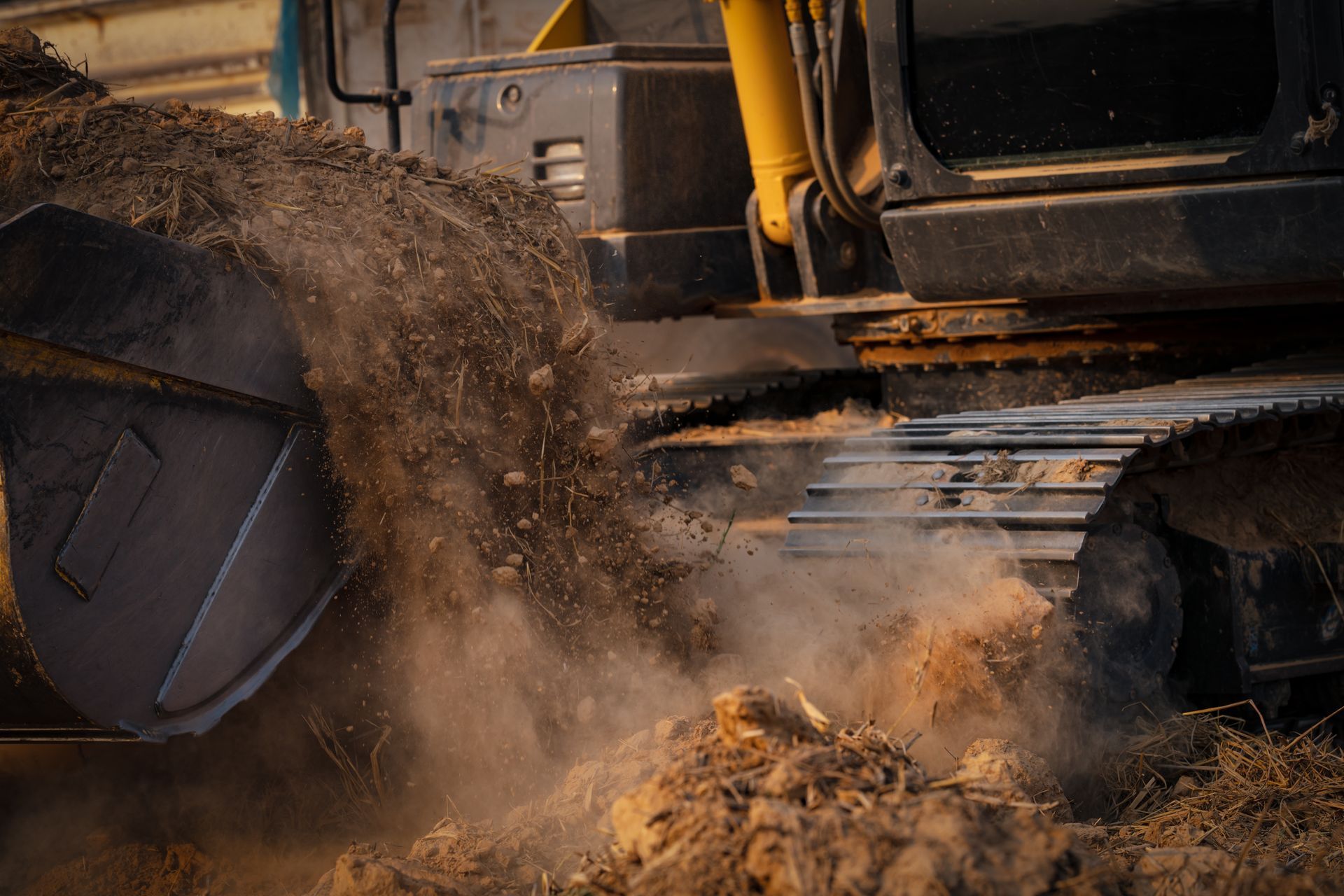 Excavator dumping dirt, creating a cloud of dust in a construction setting.