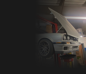 White car with hood open, on a lift in a garage. | Allen's Automotive Service