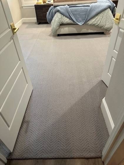 A bedroom with a bed and a rug on the floor.