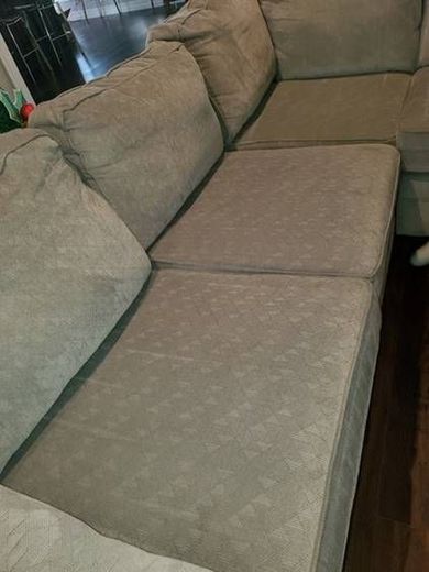 A grey sectional couch is sitting on a wooden floor in a living room.