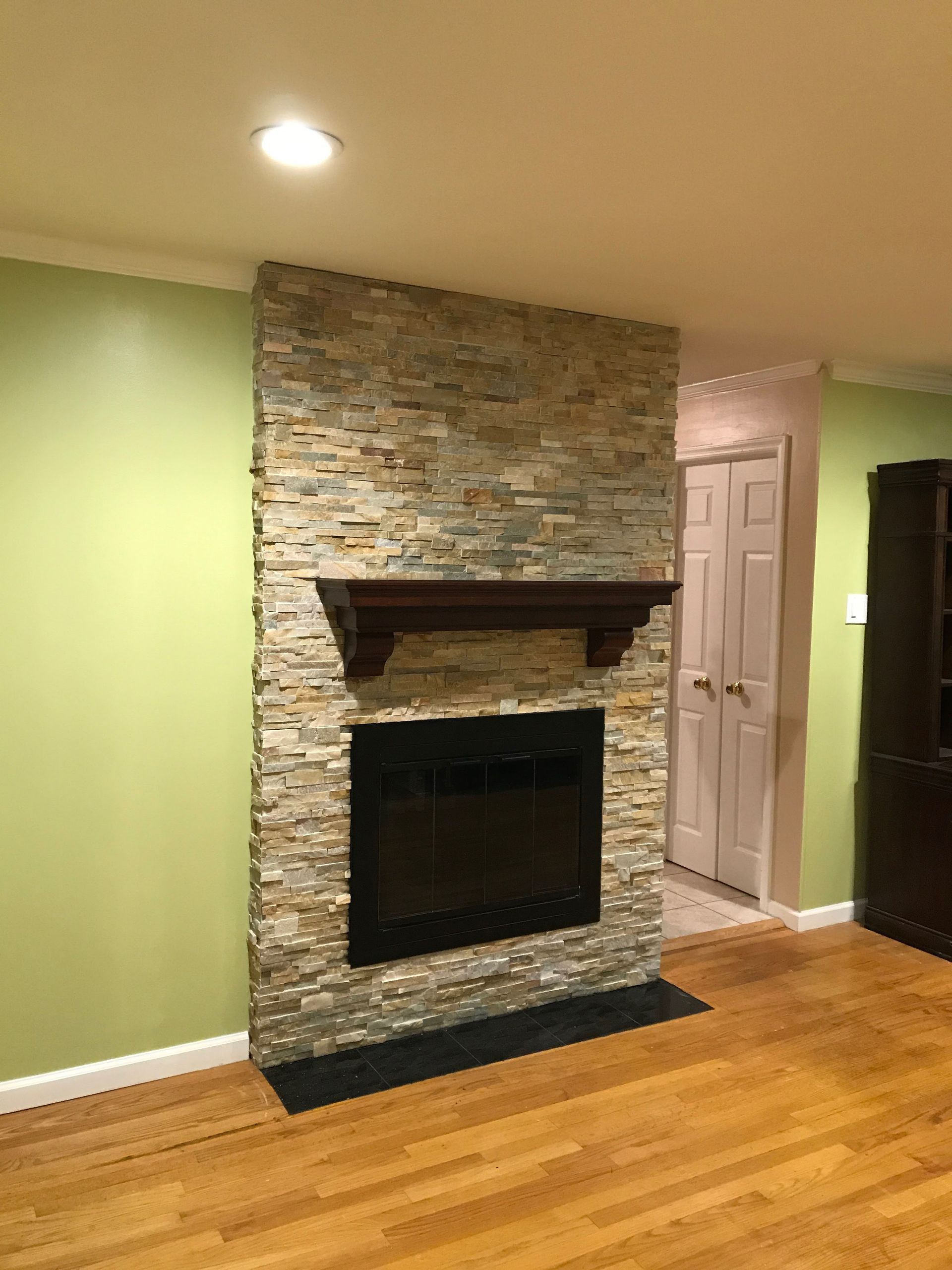 A living room with a stone fireplace and a wooden floor.