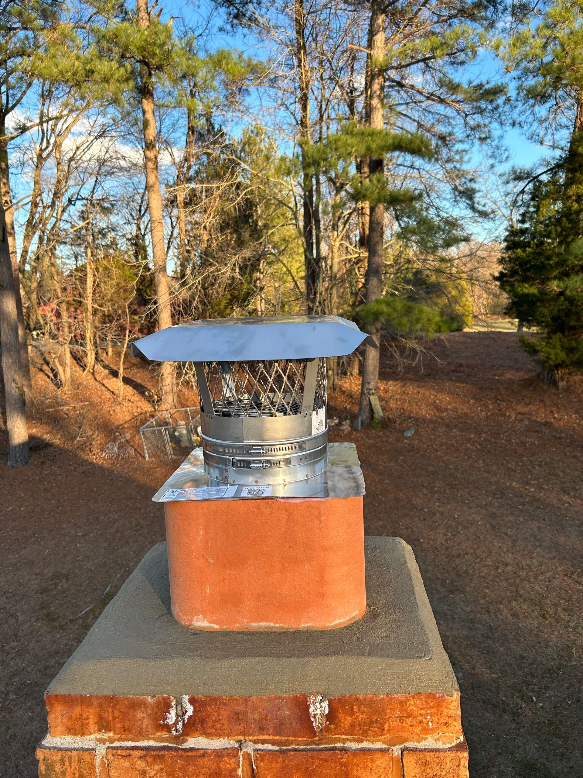 A chimney cap is sitting on top of a brick chimney.