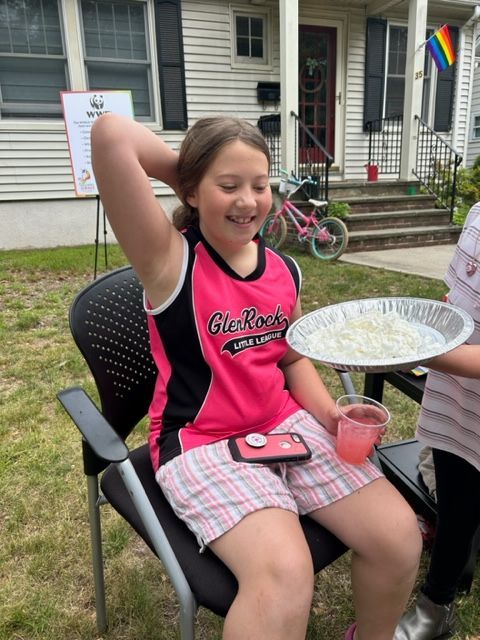 A girl in a pink shirt is sitting in a chair holding a plate of food.