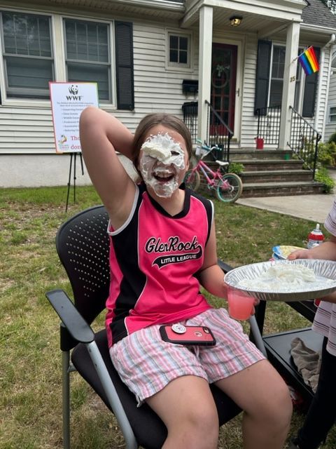 A girl with icing on her face is sitting in a chair