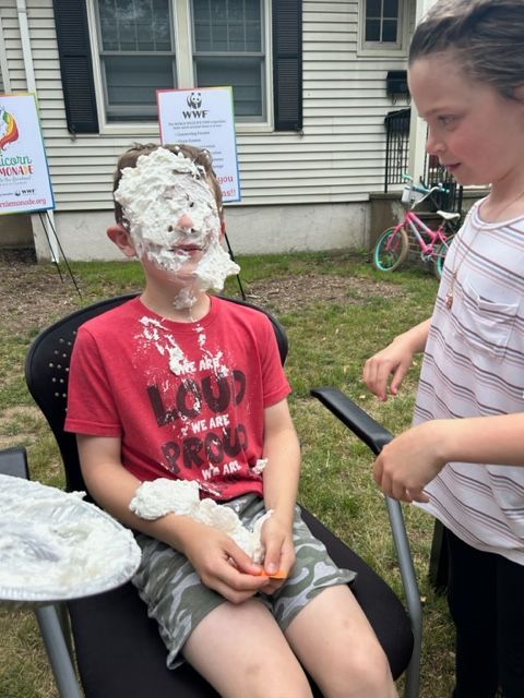 A boy in a red shirt has whipped cream on his face