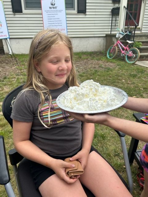 A young girl about to get a pie in the face