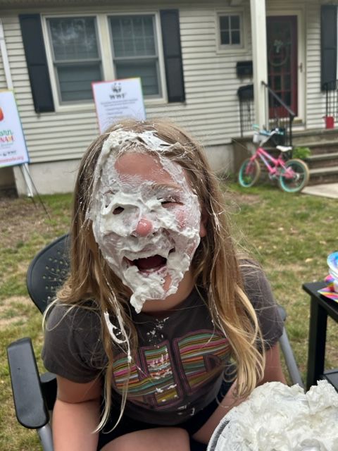 a smiling girl who got creamed by a whipped cream pie